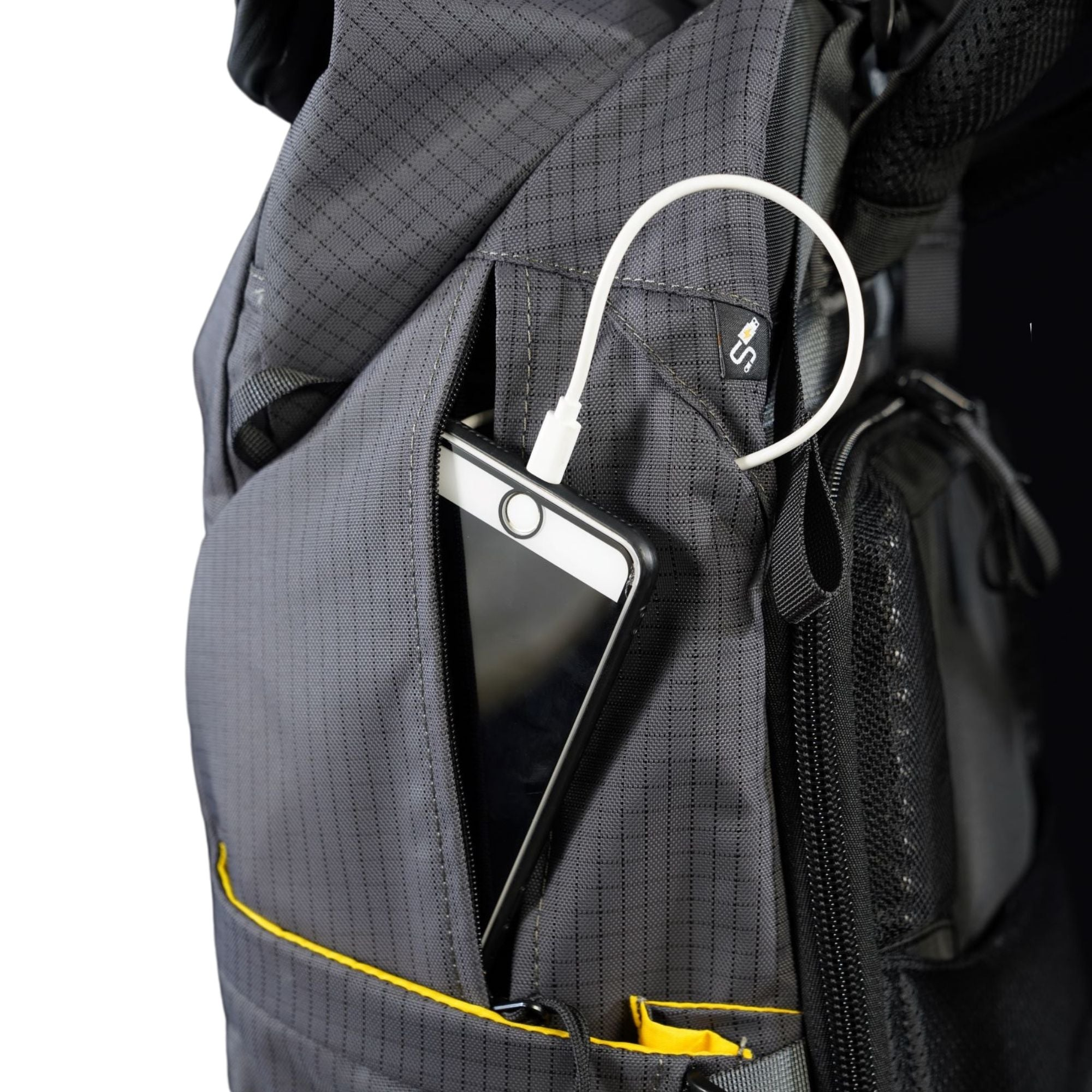 Ein Smartphone wird in eine graue Tasche mit gelber Naht gesteckt, ein weißes Ladekabel ist angeschlossen.