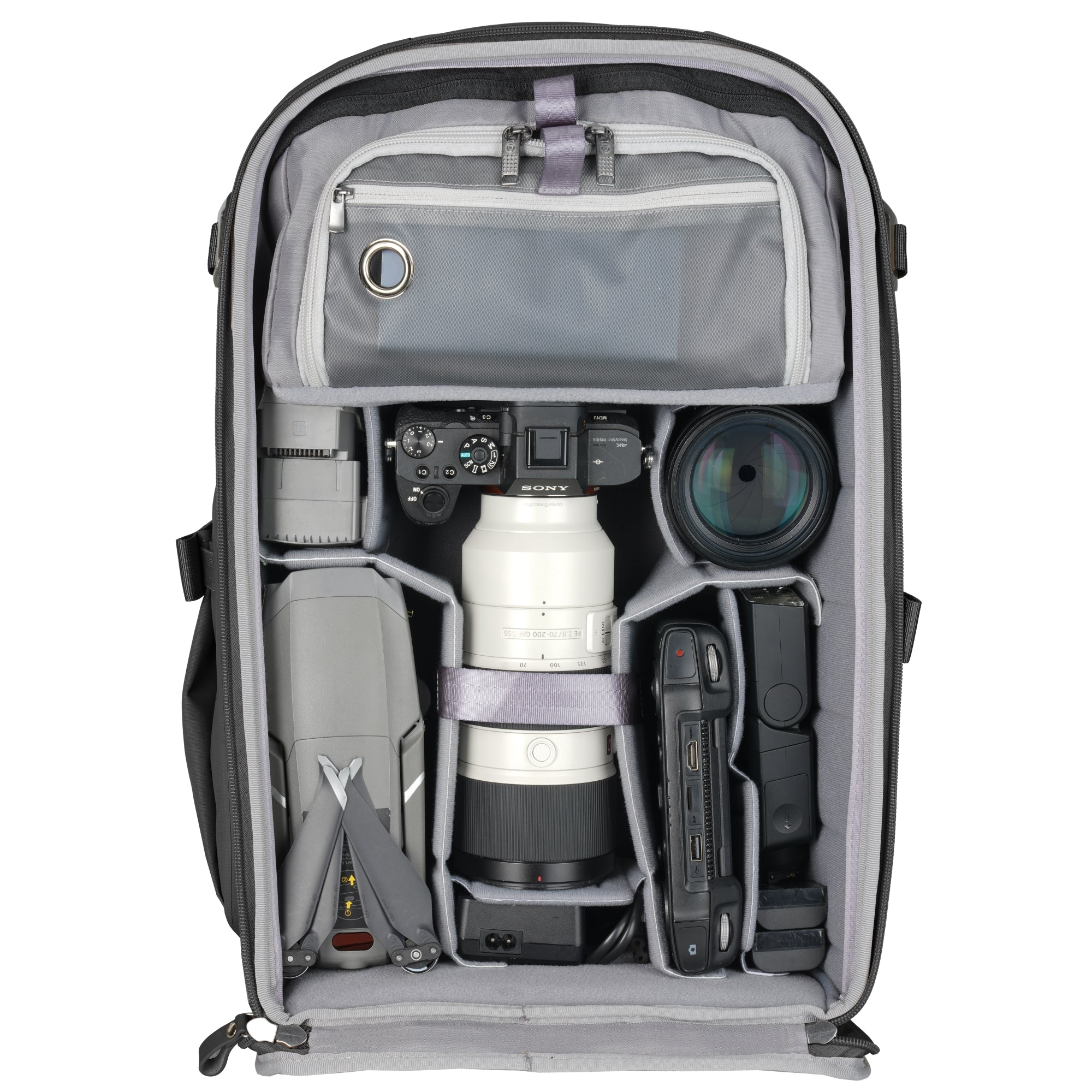 Mochila abierta con equipo fotográfico: dron, cámaras, lentes y flash.