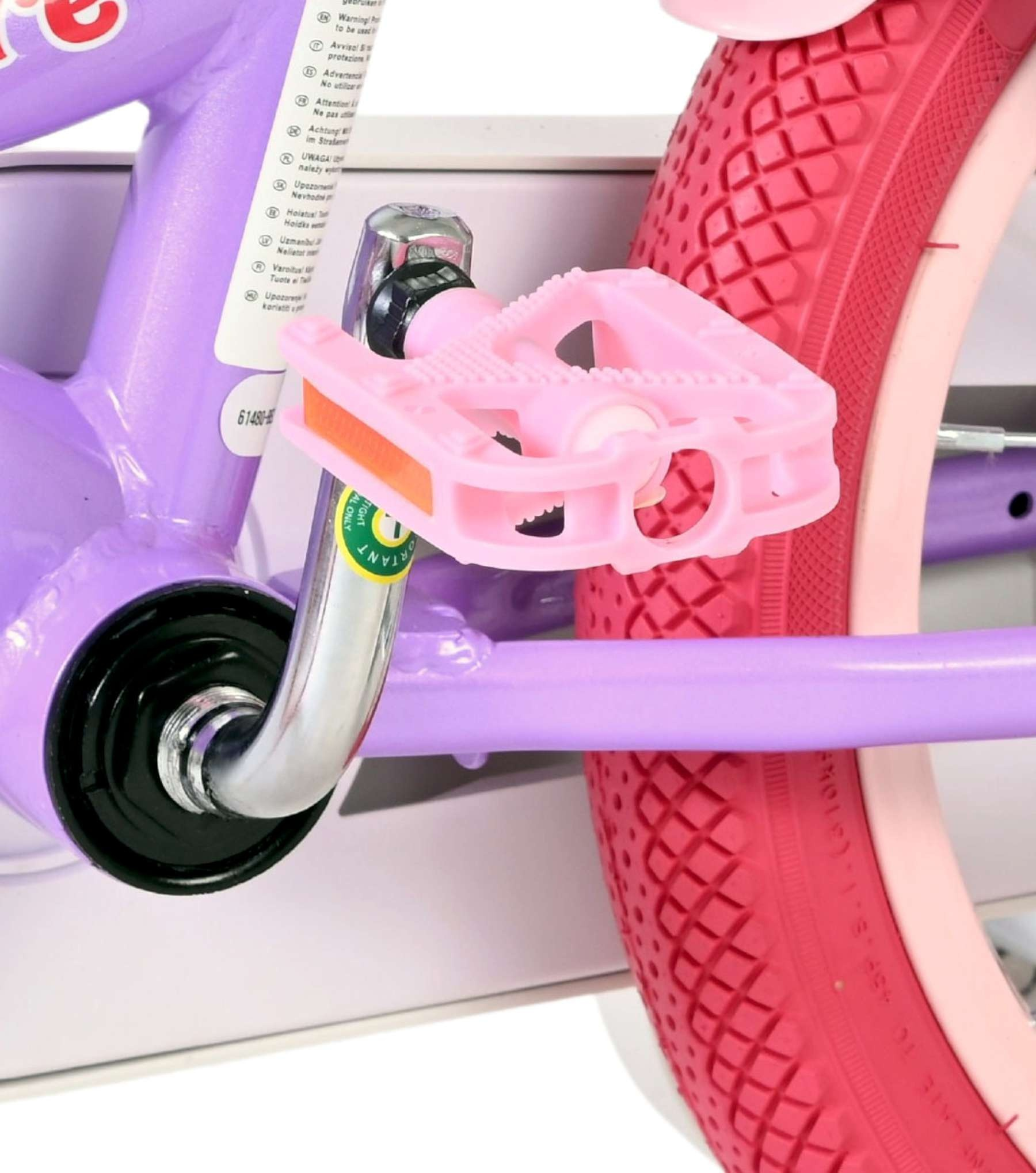 Ein pinker Fahrradpedal auf einem lila Fahrradrahmen mit rotem Reifen.