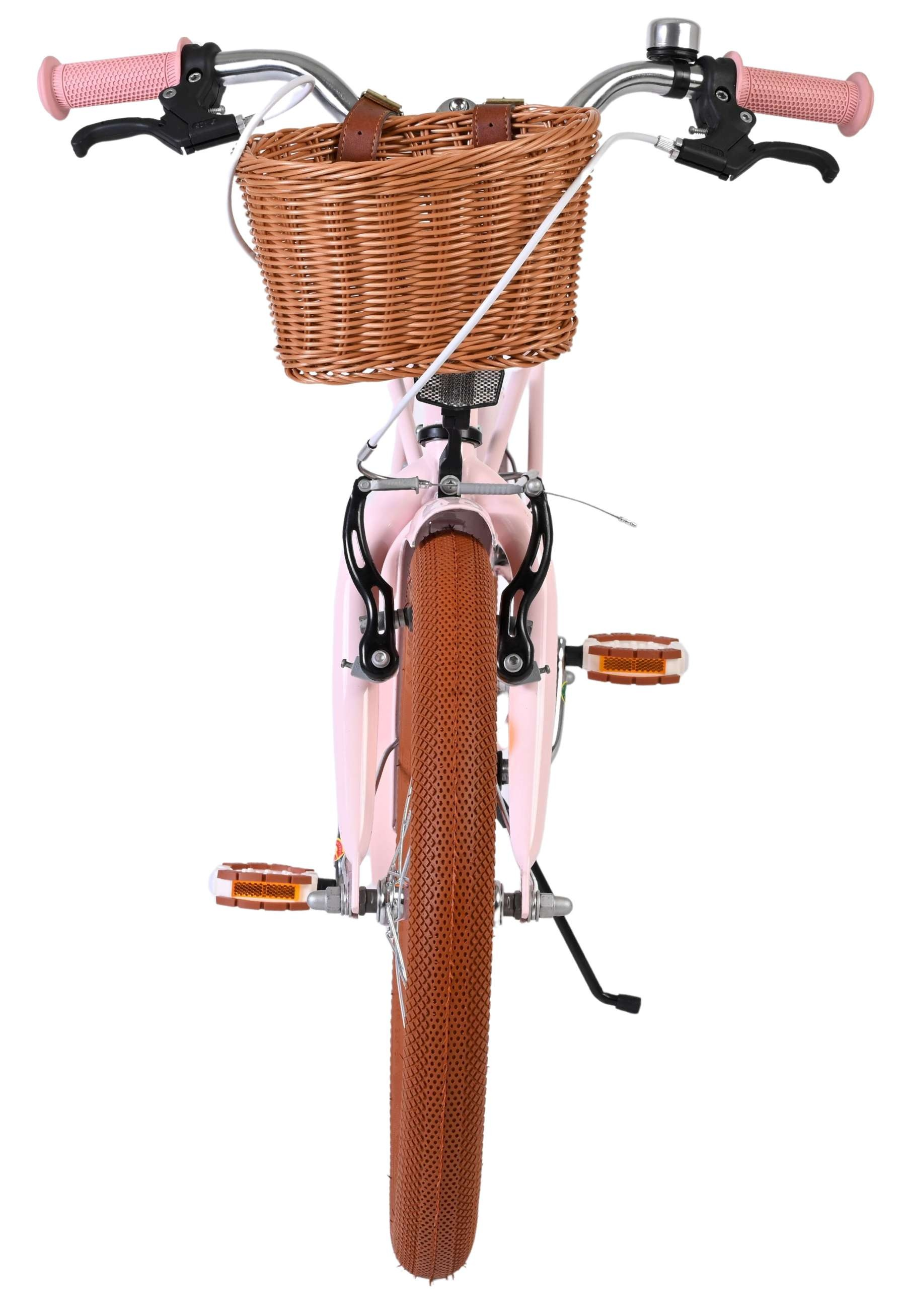 Ein rosafarbenes Kinderfahrrad mit braunem Weidenkorb und braunem Reifen.