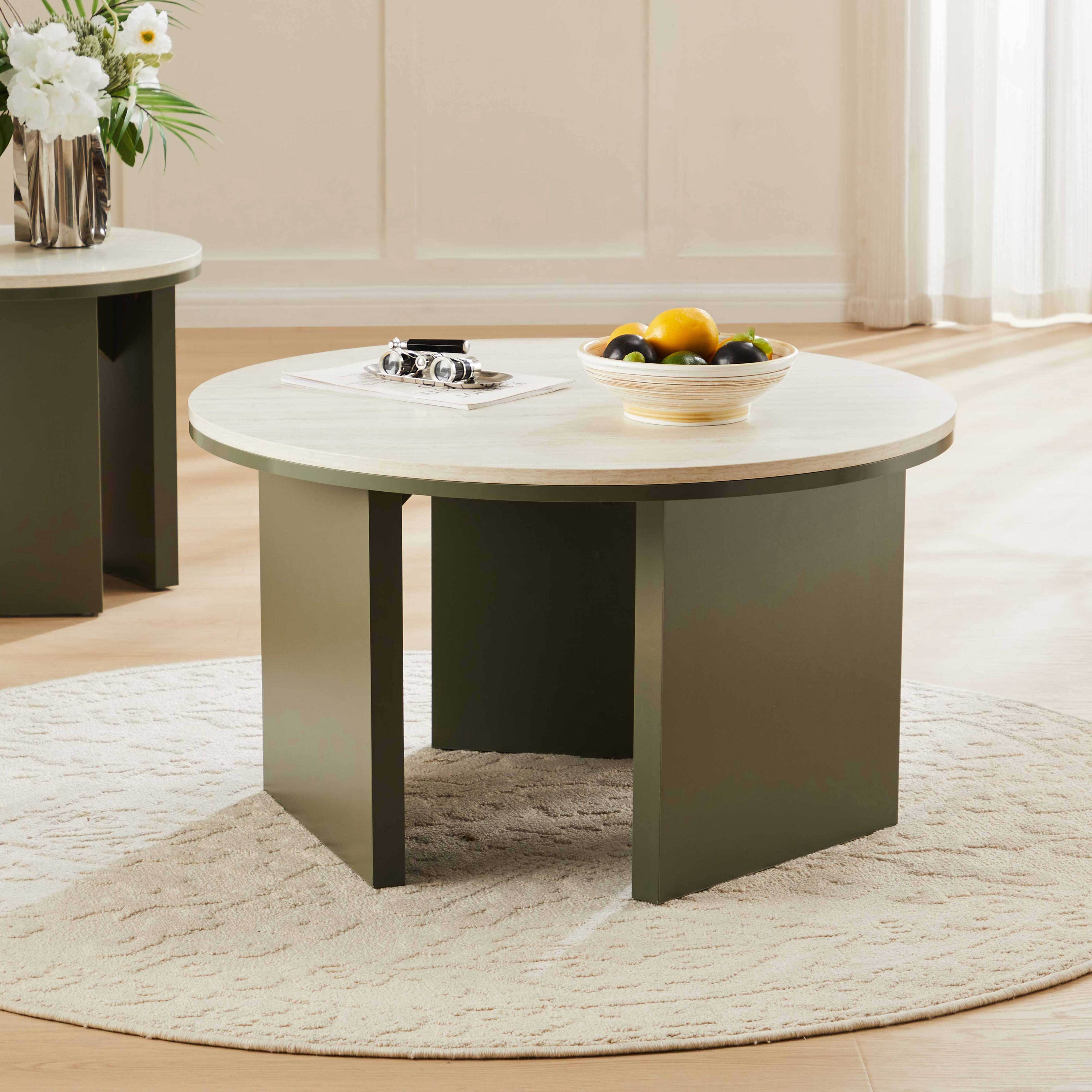 Ein runder Couchtisch mit einer Obstschale und Fernglas auf einem Teppich.