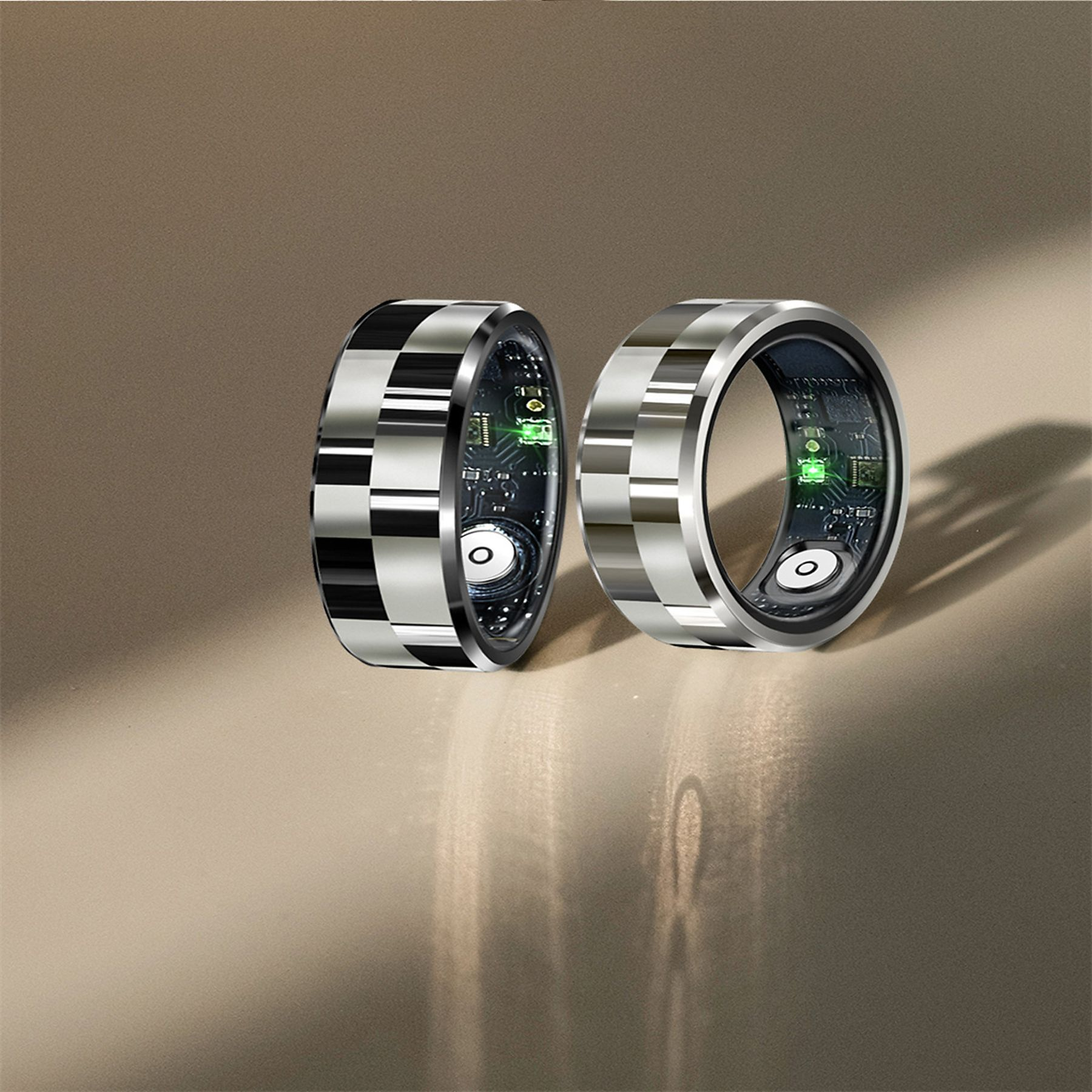 Zwei silberne Ringe mit schwarzen Quadraten und leuchtenden grünen LEDs auf der Platine.