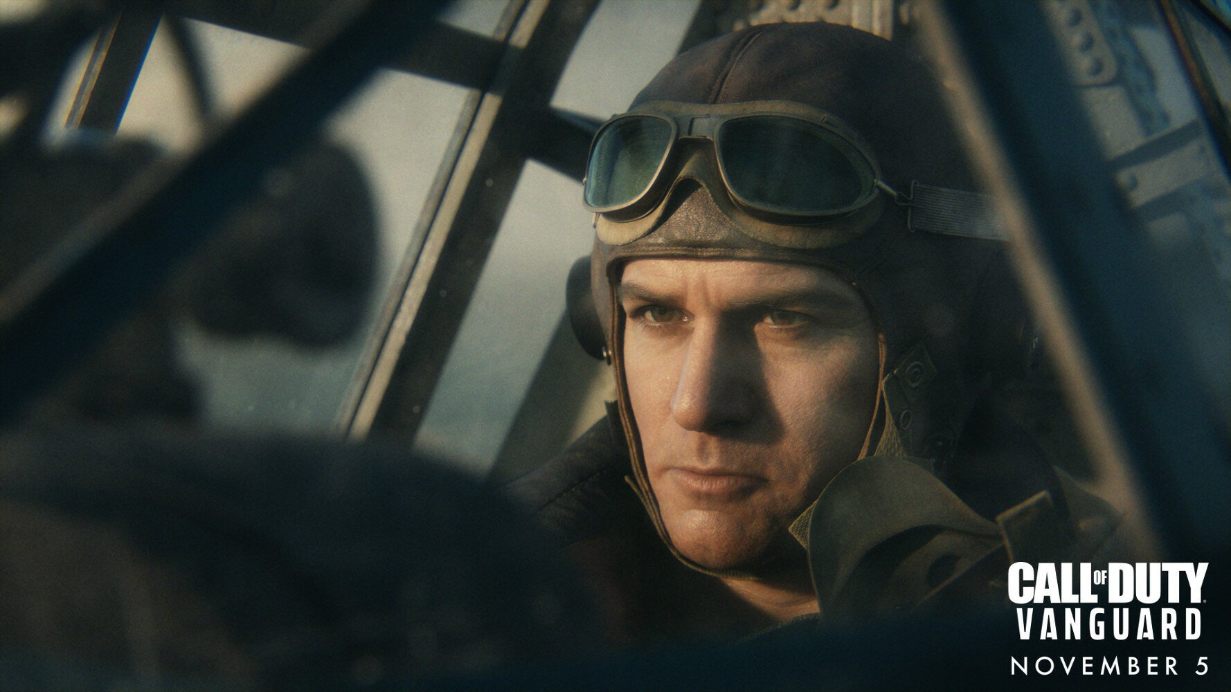 Pilot w skórzanej czapce i goglach patrzy z determinacją w kokpicie.