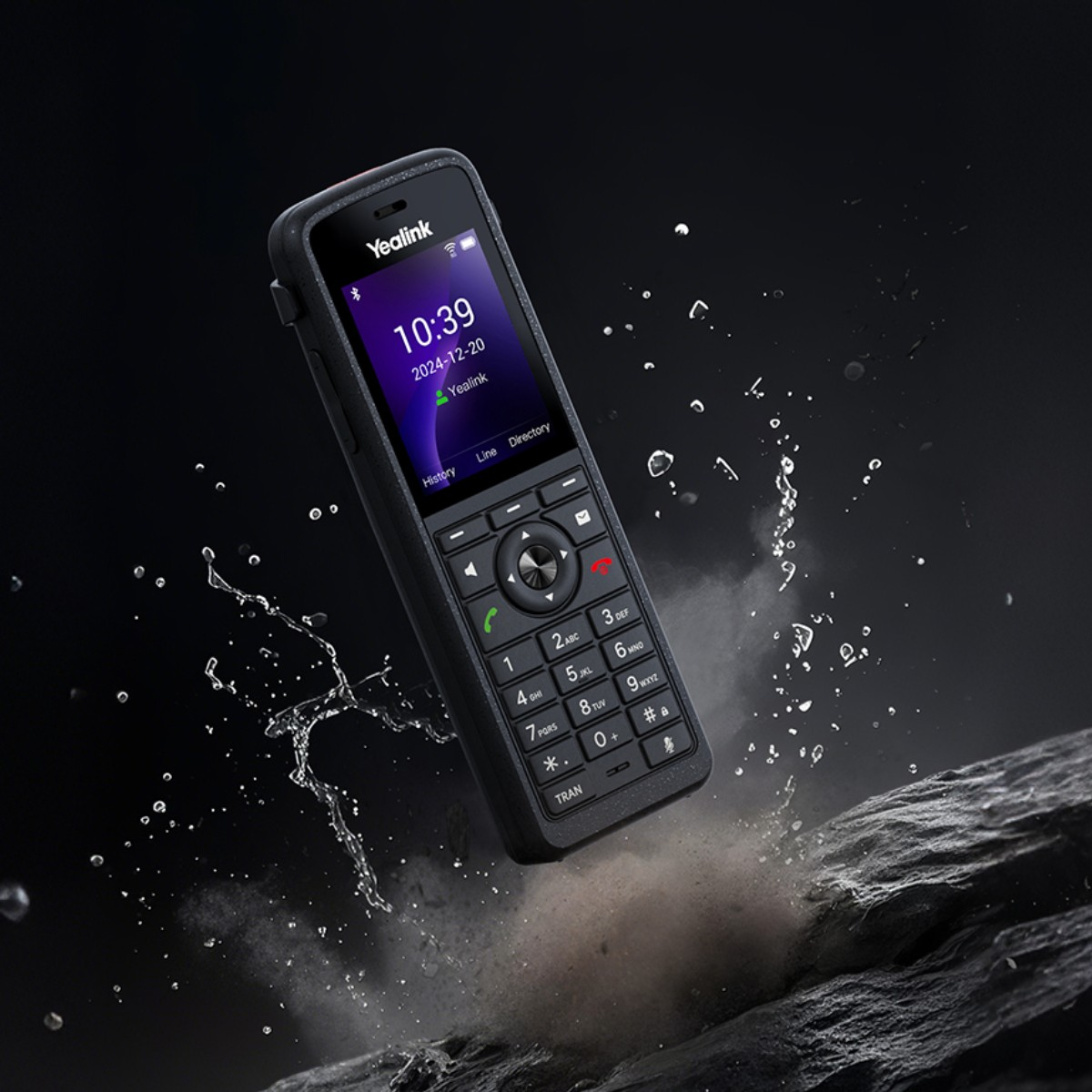 Robustes Yealink-Telefon fällt auf Felsen, Wasserspritzer umgeben es.