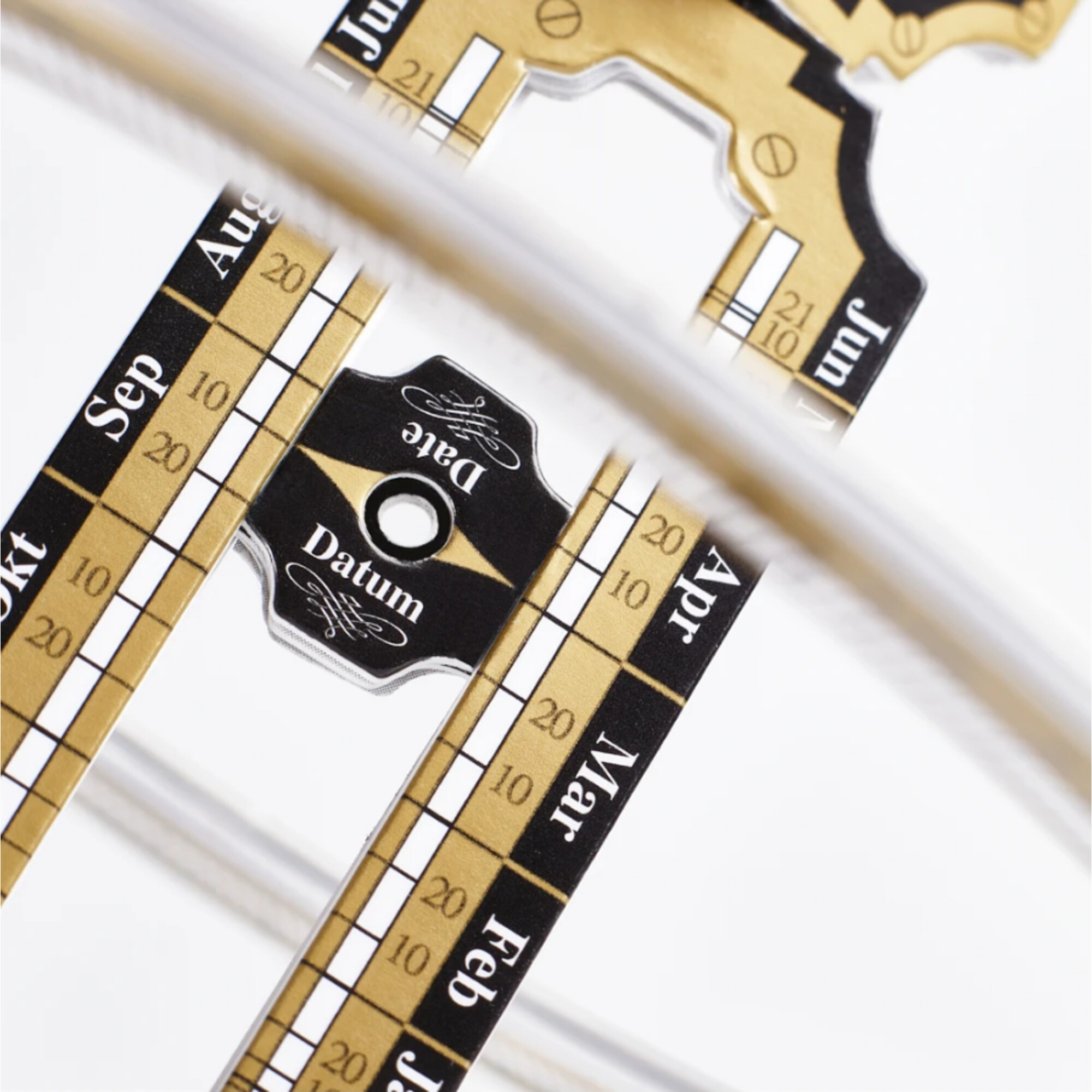 Ein Kalenderblatt mit Monatsnamen und Zahlen auf Gold- und Schwarzem Hintergrund.