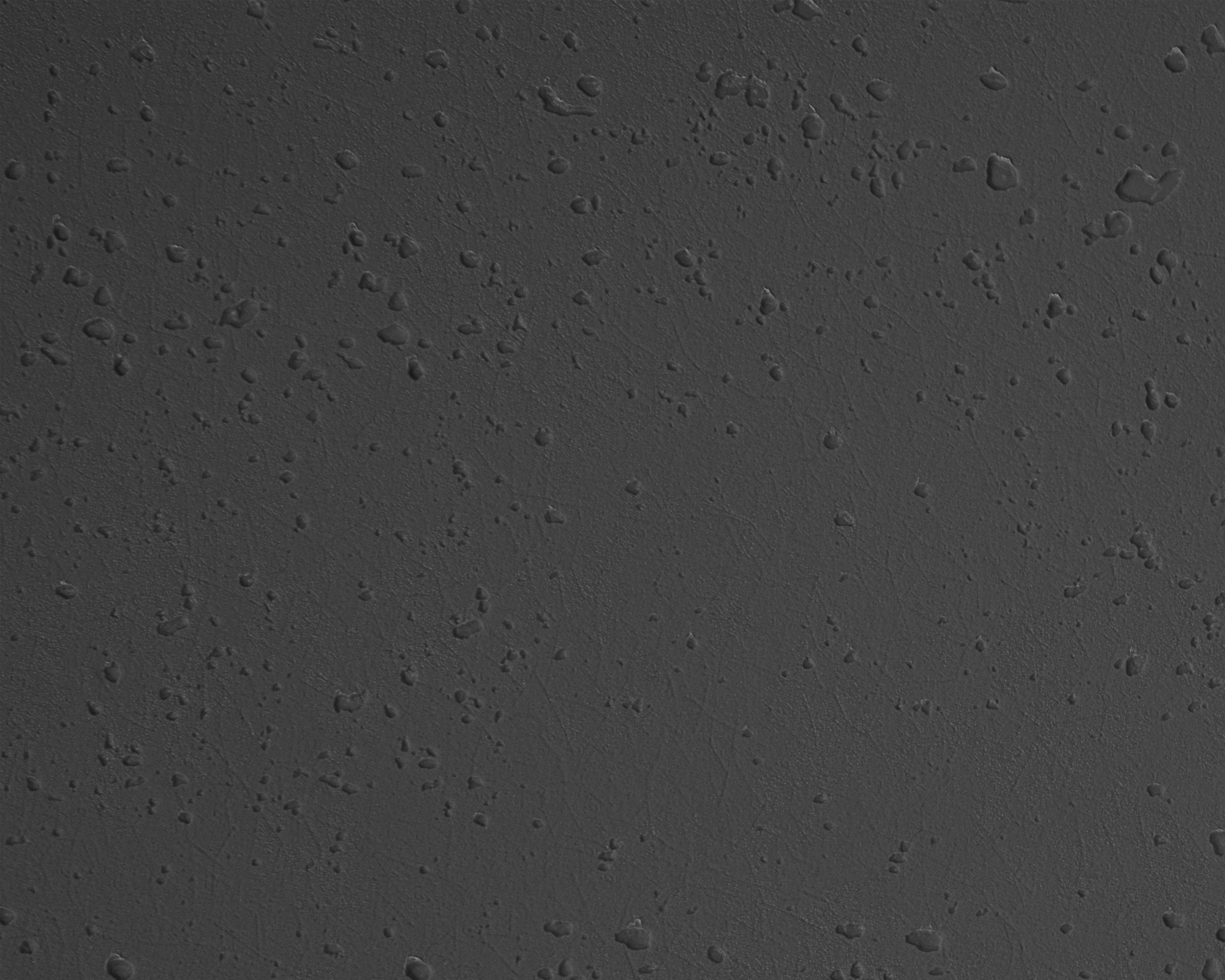 Graue Oberfläche mit unregelmäßigen, kleinen Wassertropfen.