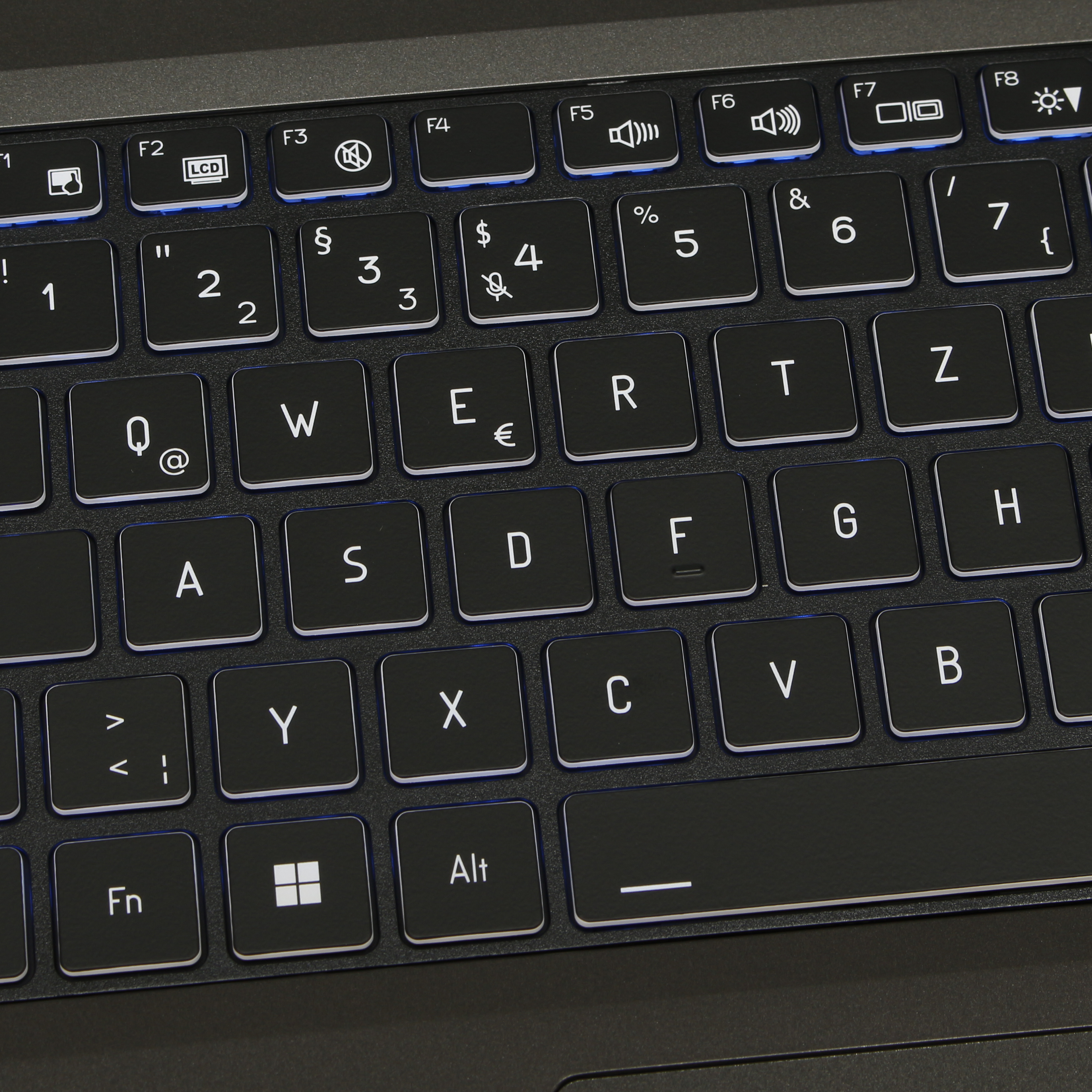 Primer plano de un teclado negro con retroiluminación azul.