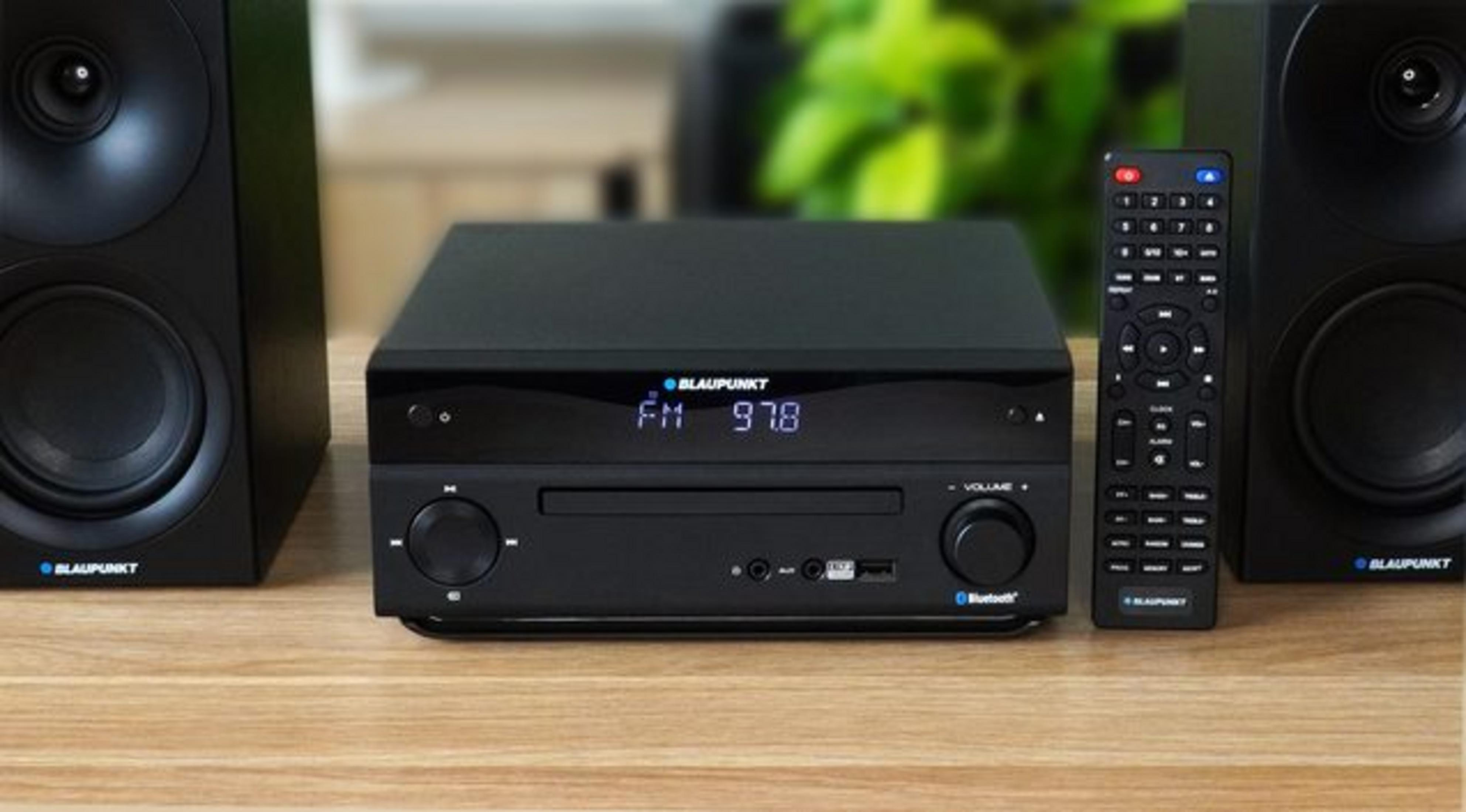 Un stereo con lettore CD, due altoparlanti e telecomando su tavolo di legno.