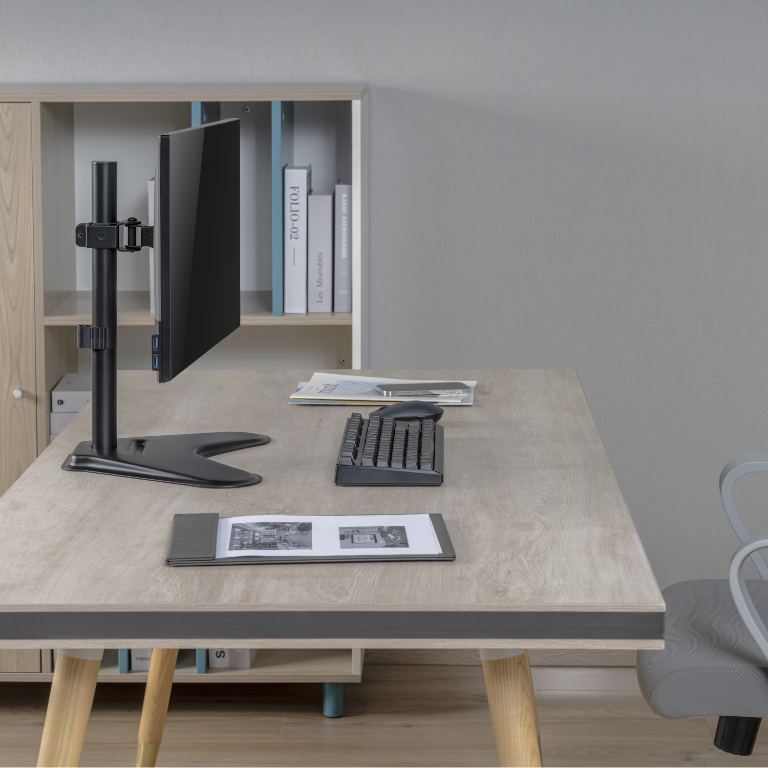 Una scrivania con monitor, tastiera, mouse e documenti.