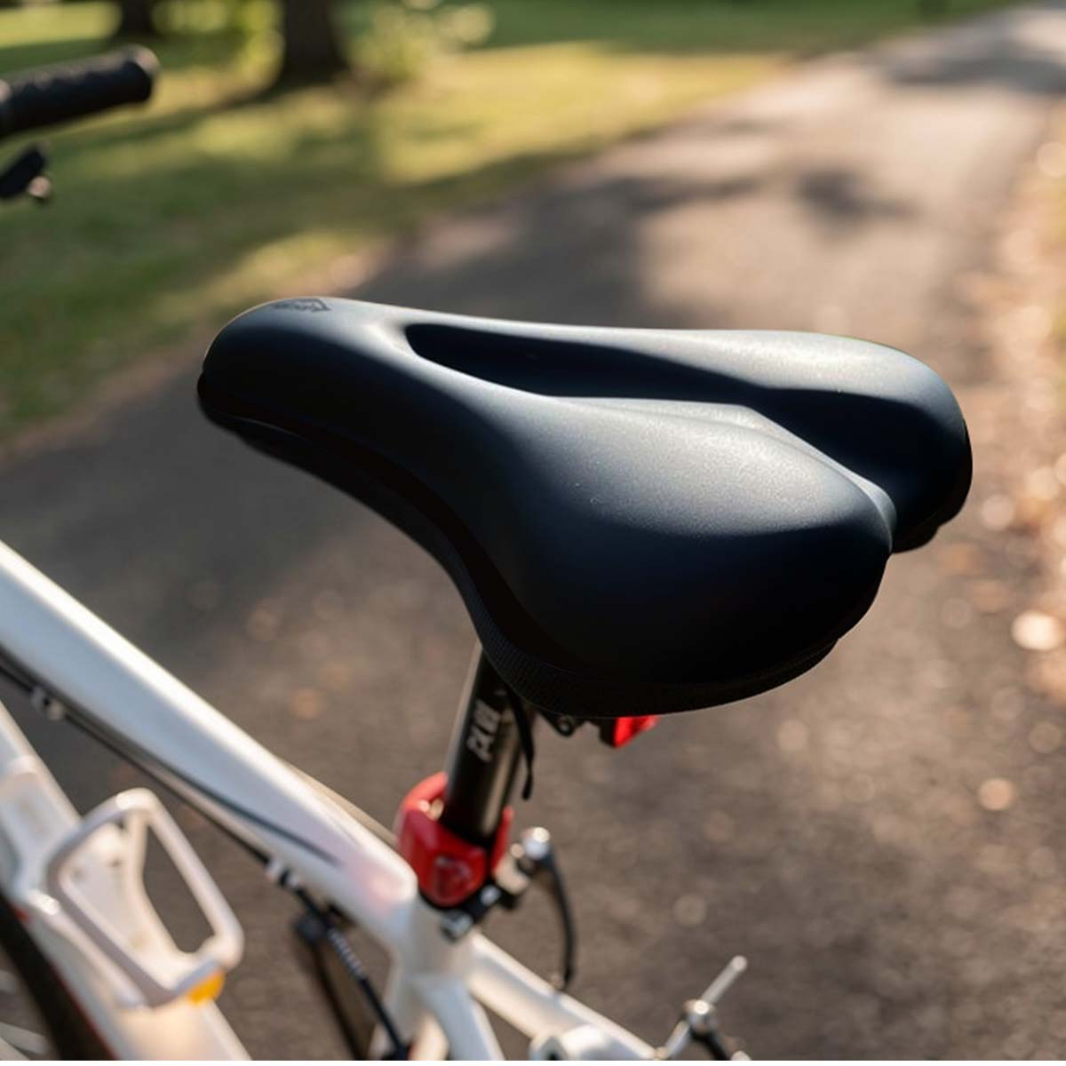 Selle de vélo noire sur un vélo blanc avec feu arrière rouge.