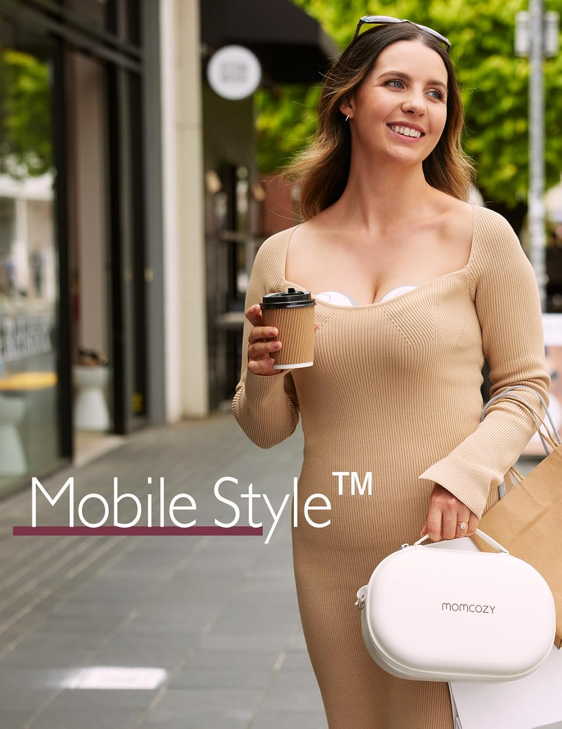 Kobieta w beżowej sukience trzyma kawę i torbę, idąc na zewnątrz.