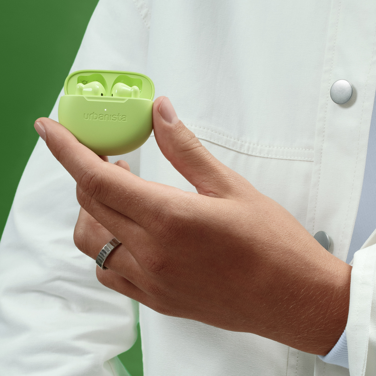 Green Urbanista case with earbuds, held in hand.