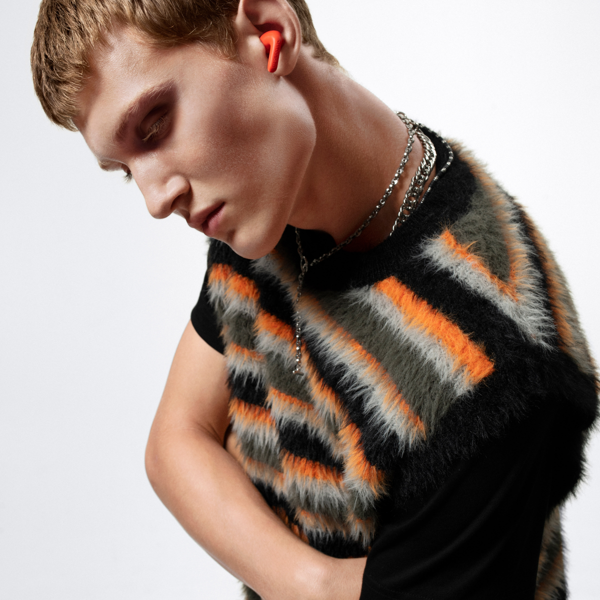 Un uomo con auricolari arancioni indossa un gilet a righe.