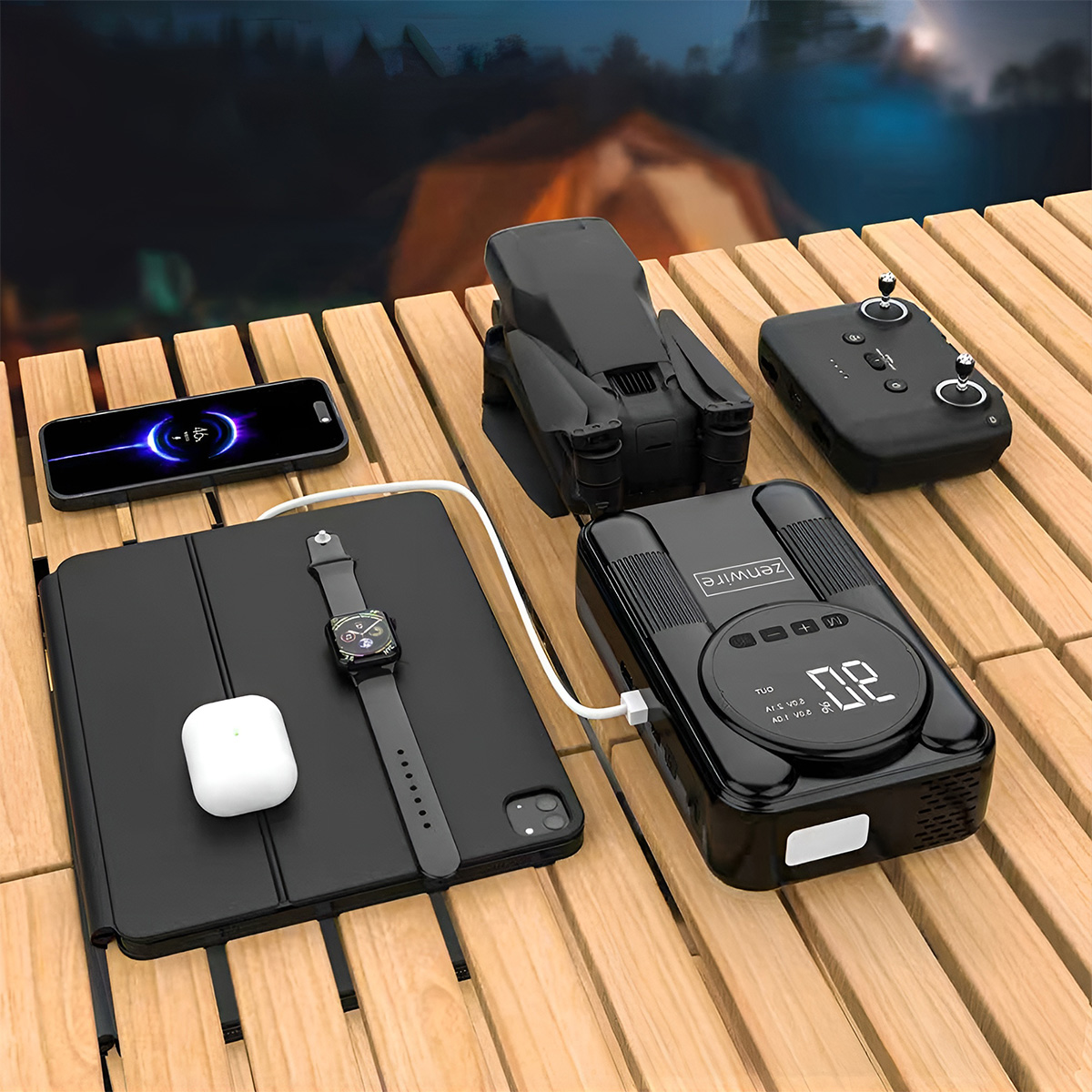 Czarny zestaw drona z ładowarką, pilotem, tabletem, zegarkiem i telefonem na drewnianym stole.