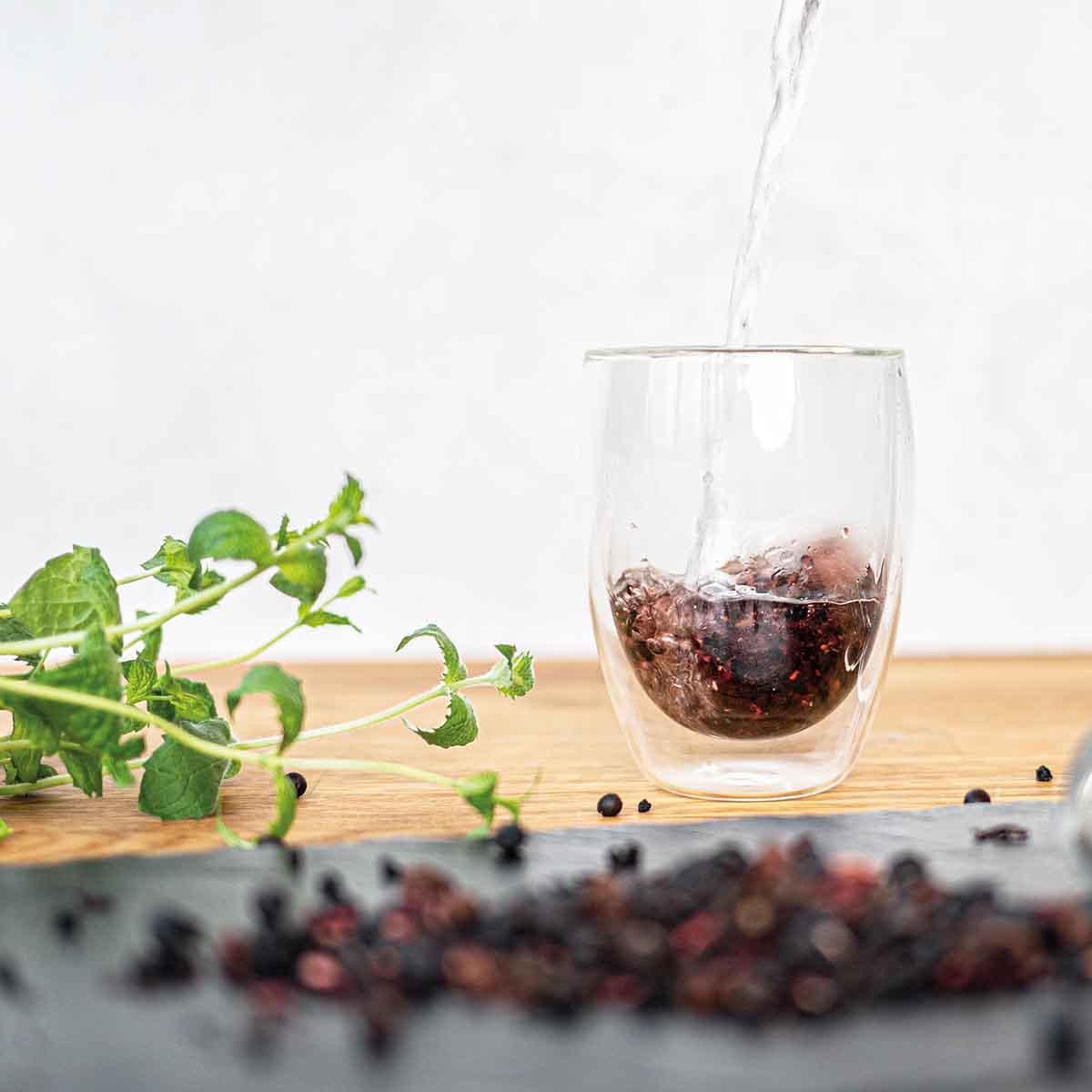 Woda jest nalewana do szklanki z jagodami i miętą.