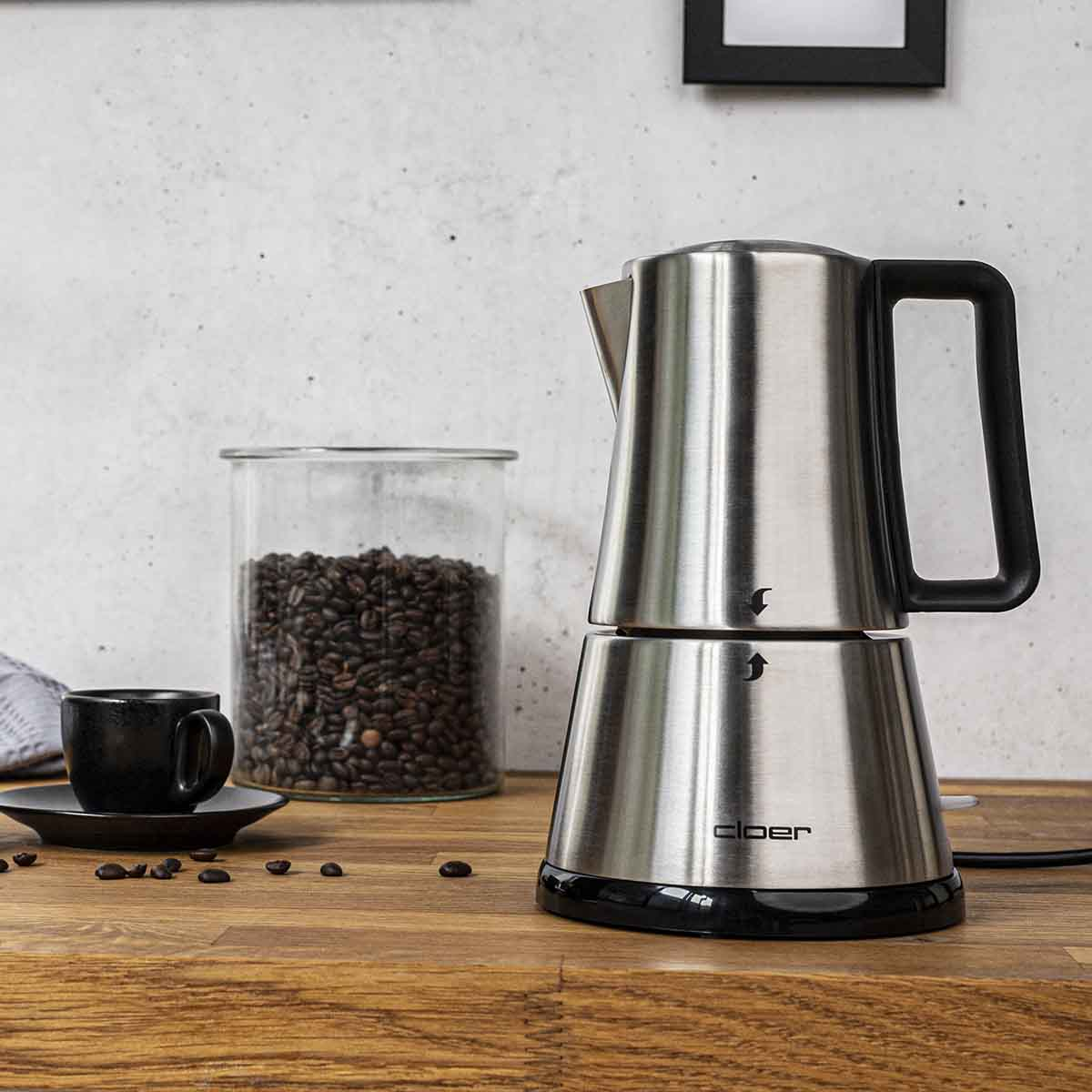Moka in acciaio inox con barattolo di chicchi, tazzina nera.
