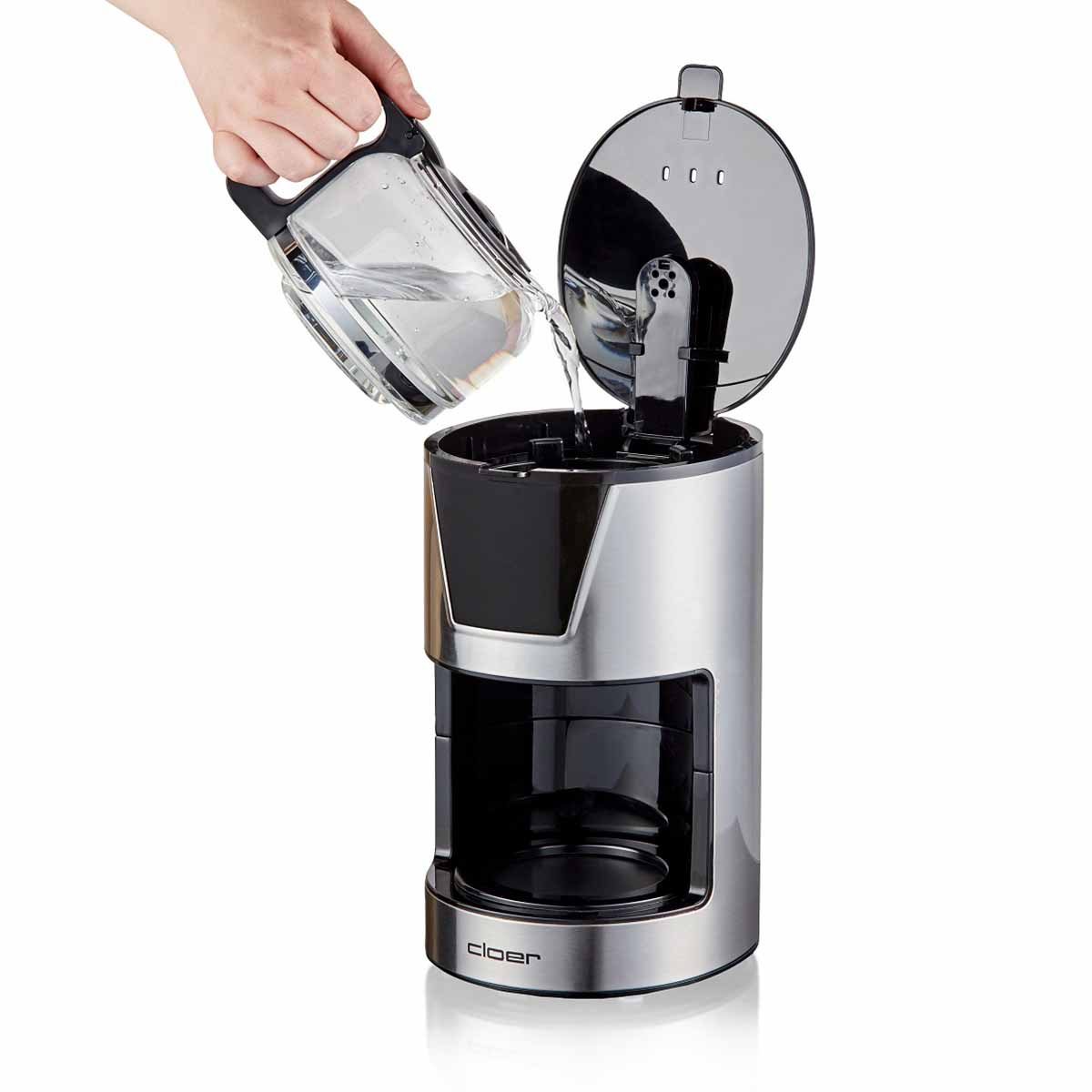 Ręka przelewa wodę z szklanego dzbanka do ekspresu do kawy.