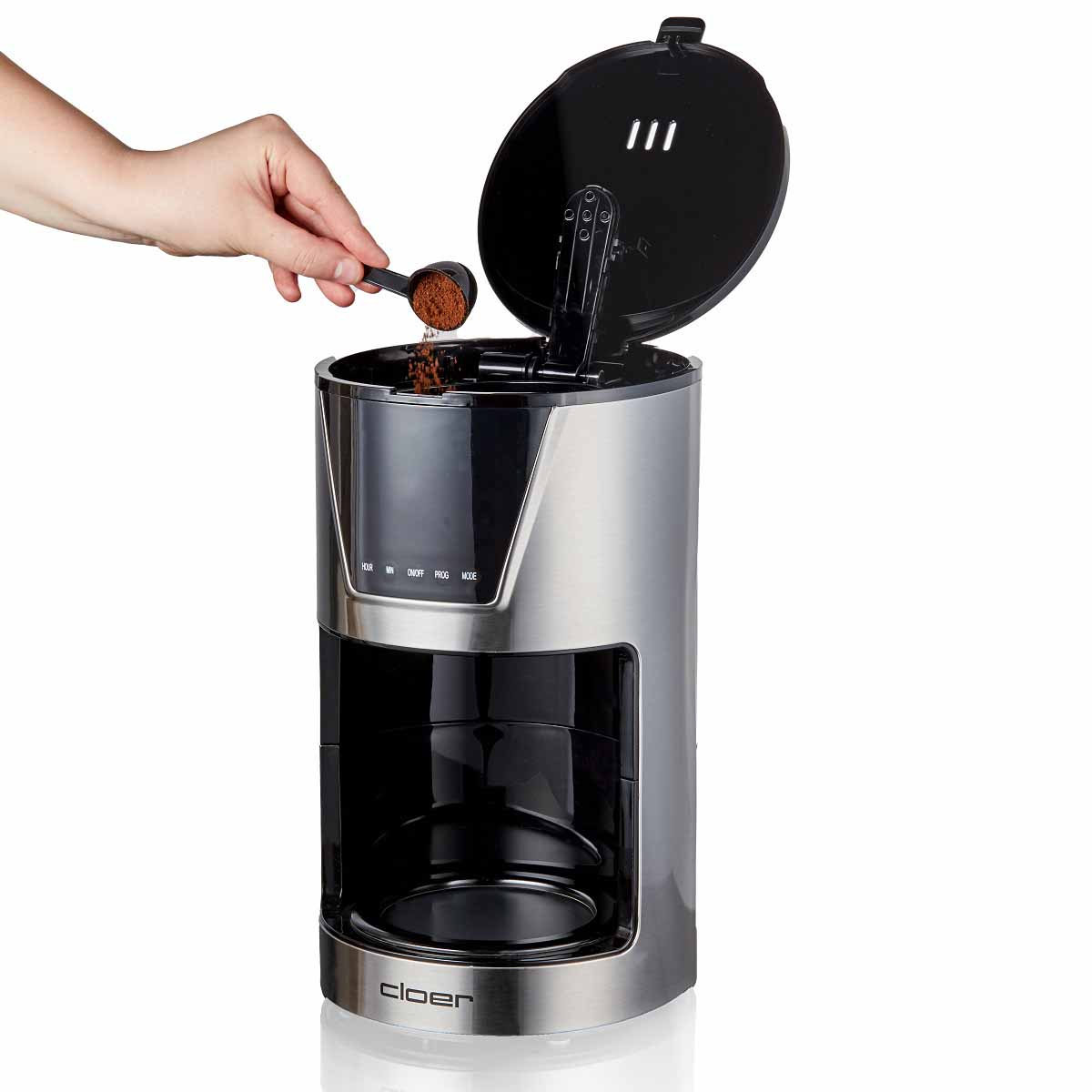 Ręka wsypuje kawę mieloną łyżką do ekspresu do kawy.