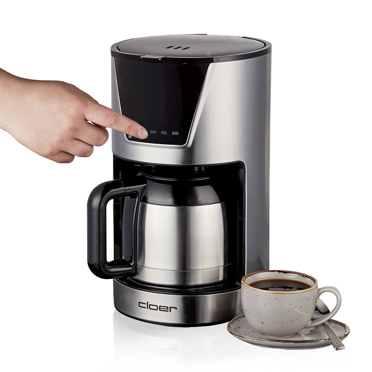 Dłoń naciska przycisk włączania/wyłączania ekspresu do kawy obok filiżanki kawy.