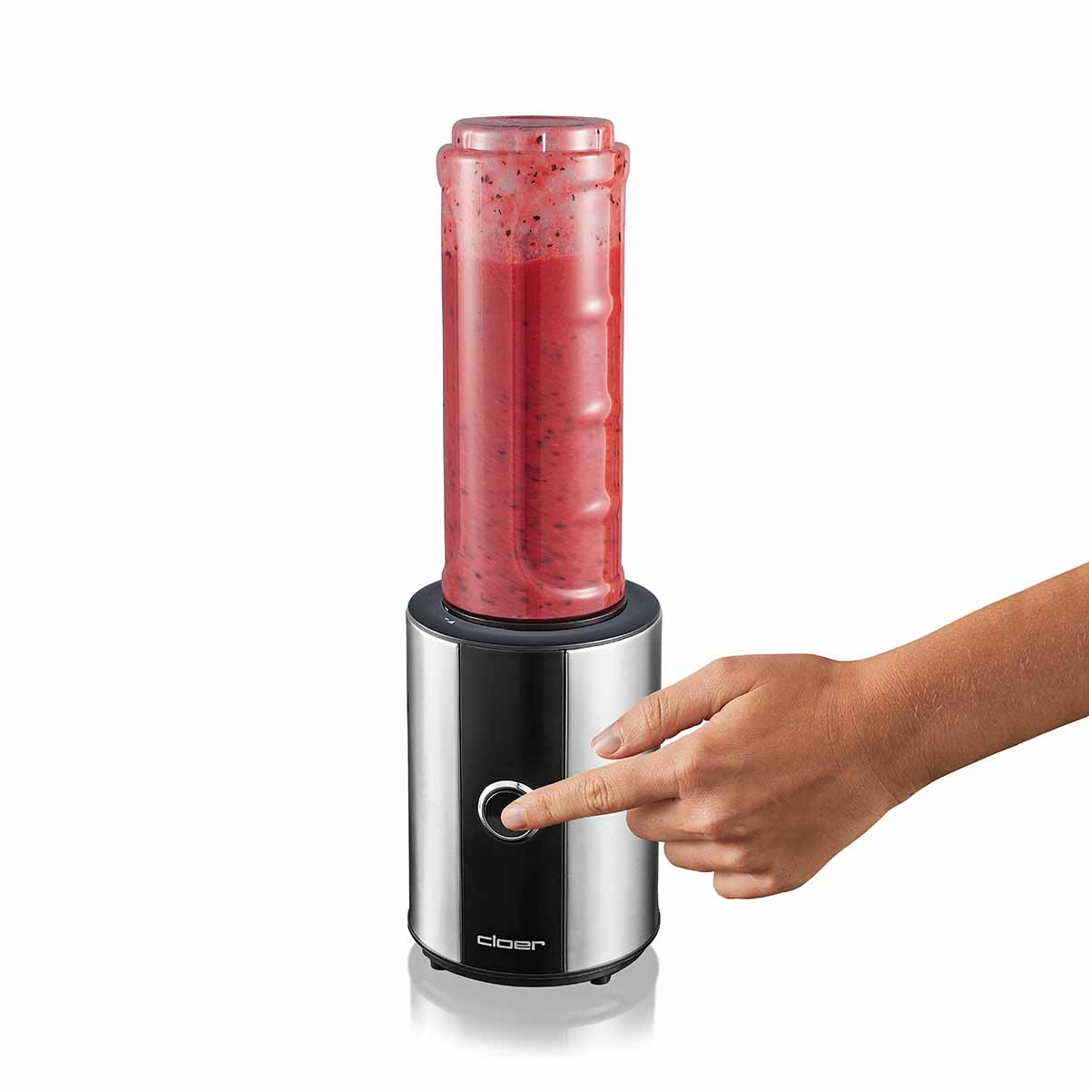 Eine Hand drückt den Knopf eines silbernen Mixers mit rotem Smoothie.