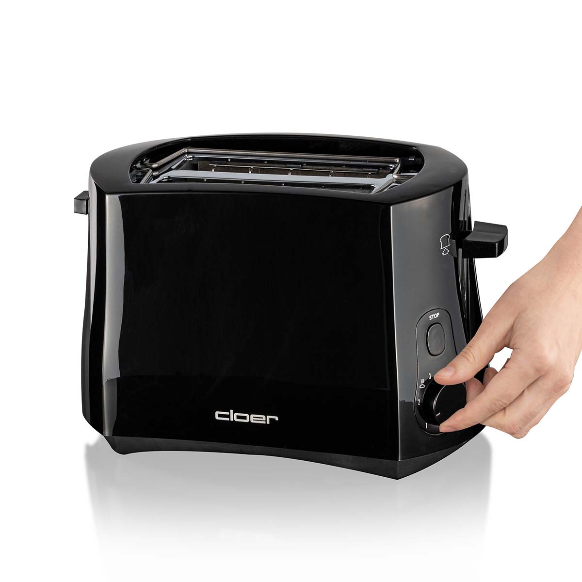 Eine schwarze Toaster wird von einer Hand bedient, die den Drehregler einstellt.