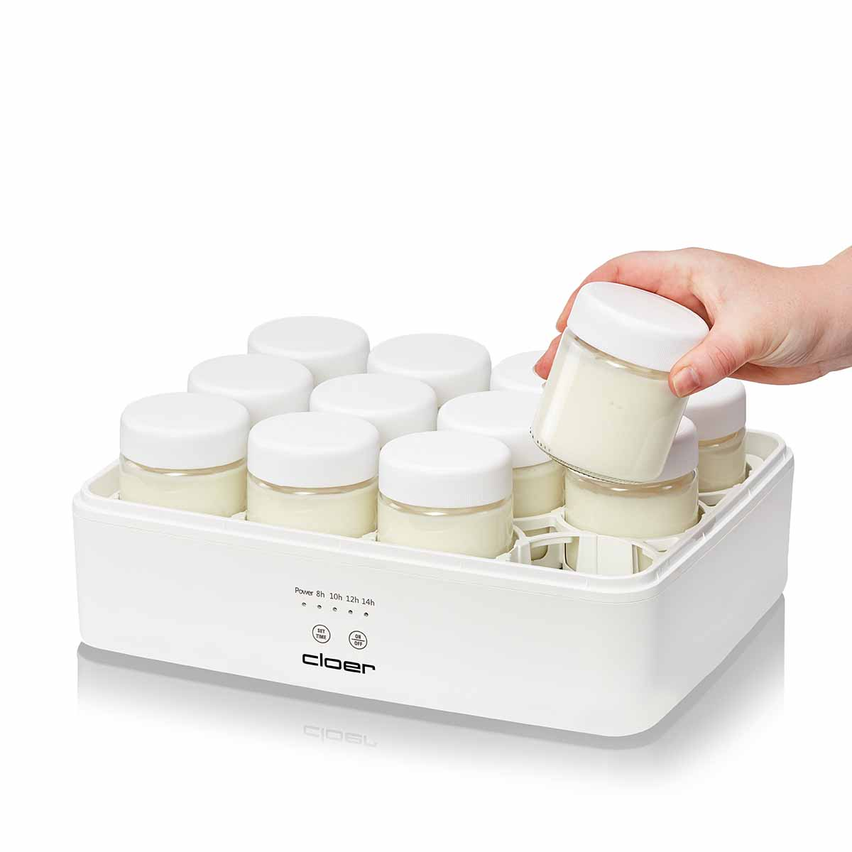 Eine Hand nimmt ein Glas mit Joghurt aus einem weißen Joghurtbereiter mit vielen Gläsern.