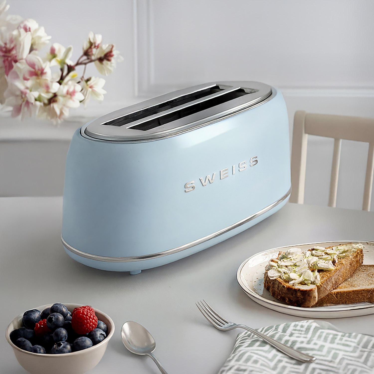 Un tostapane azzurro su un tavolo con bacche, toast e fiori.