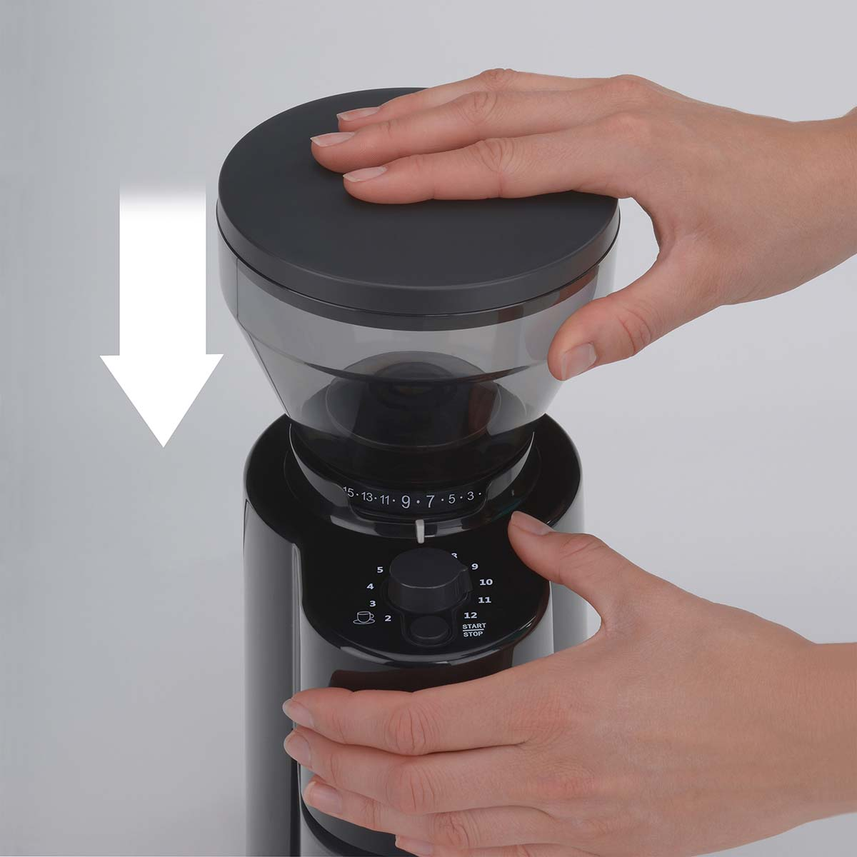 Hände bedienen eine schwarze Kaffeemühle mit Einstellrad und Behälter.