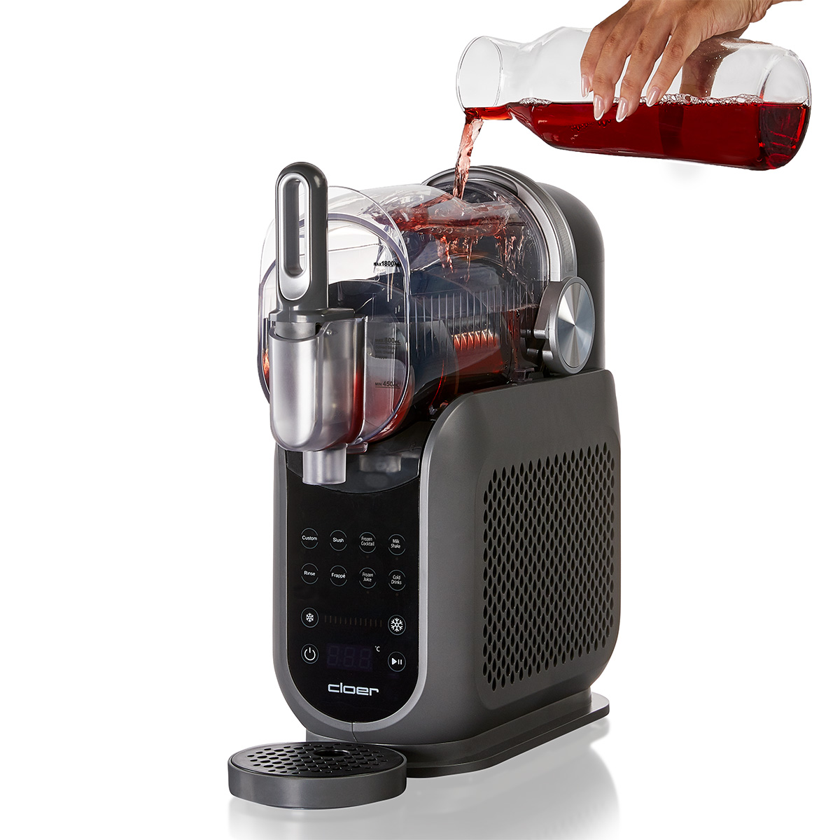Una mano versa succo rosso da una caraffa di vetro in una gelatiera.