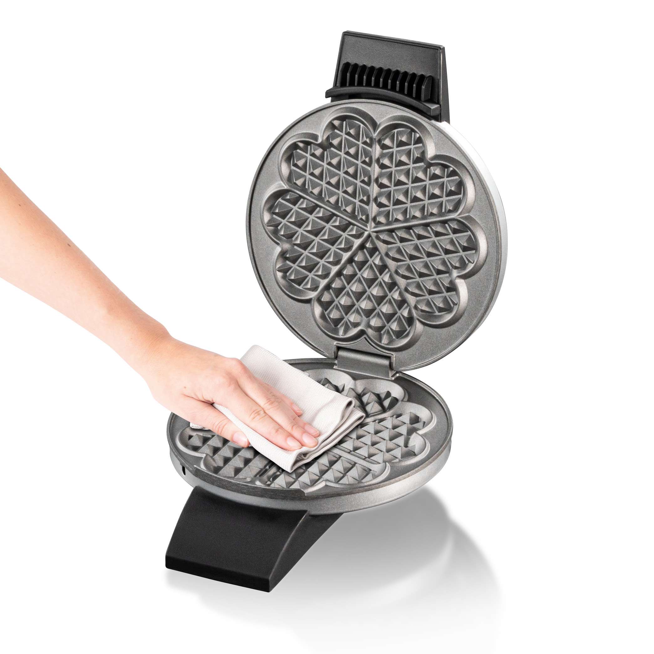 Ręka czyści gofrownicę w kształcie serca ściereczką.