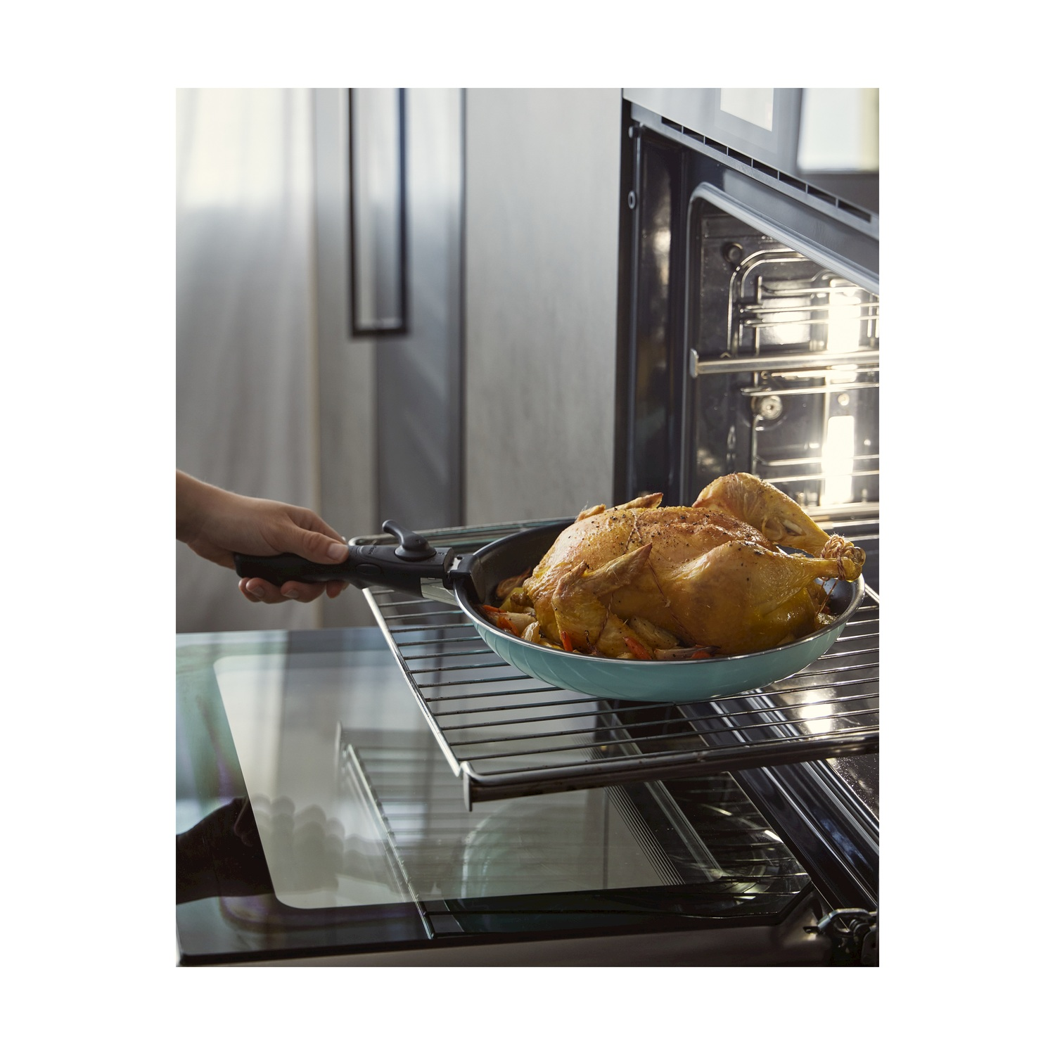 Un pollo arrosto dorato viene tolto da un forno su una griglia.