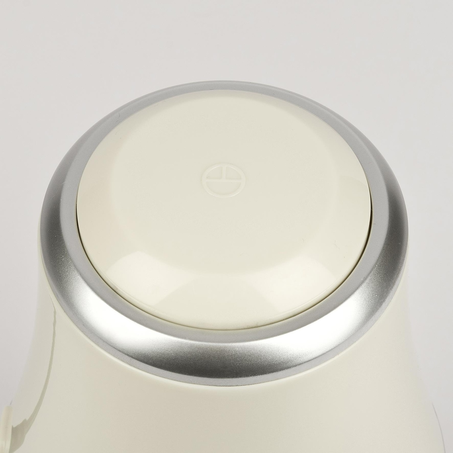 Coperchio color crema con anello argentato, logo al centro.