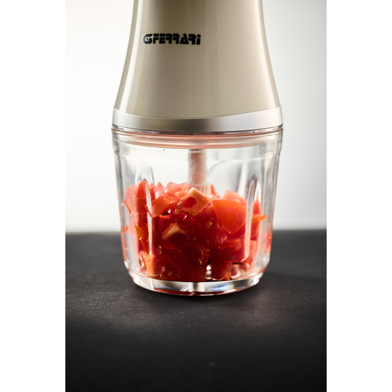 Un primo piano di un tritatutto da cucina con pomodori tritati nel suo contenitore di vetro.