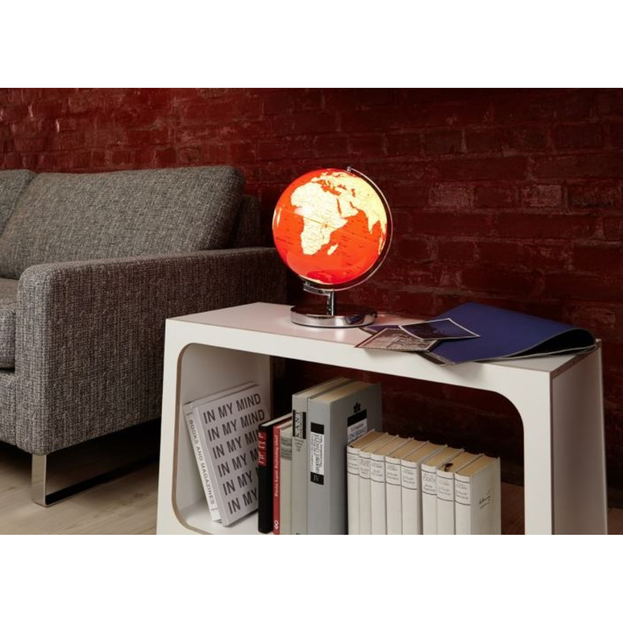 Ein beleuchteter Globus steht auf einem Beistelltisch neben einem Sofa.