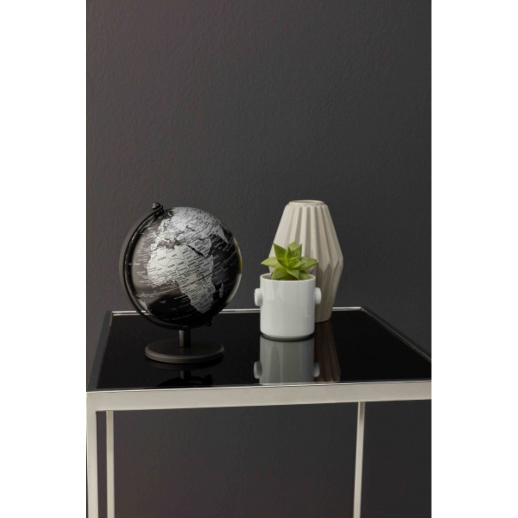 Ein Globus, eine Pflanze in einem Topf und eine Vase auf einem Tisch.