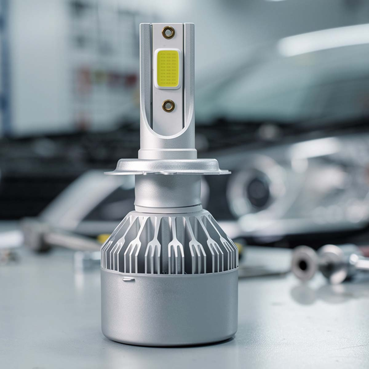 Silberner LED-Scheinwerfer auf einem Tisch, Auto im Hintergrund.