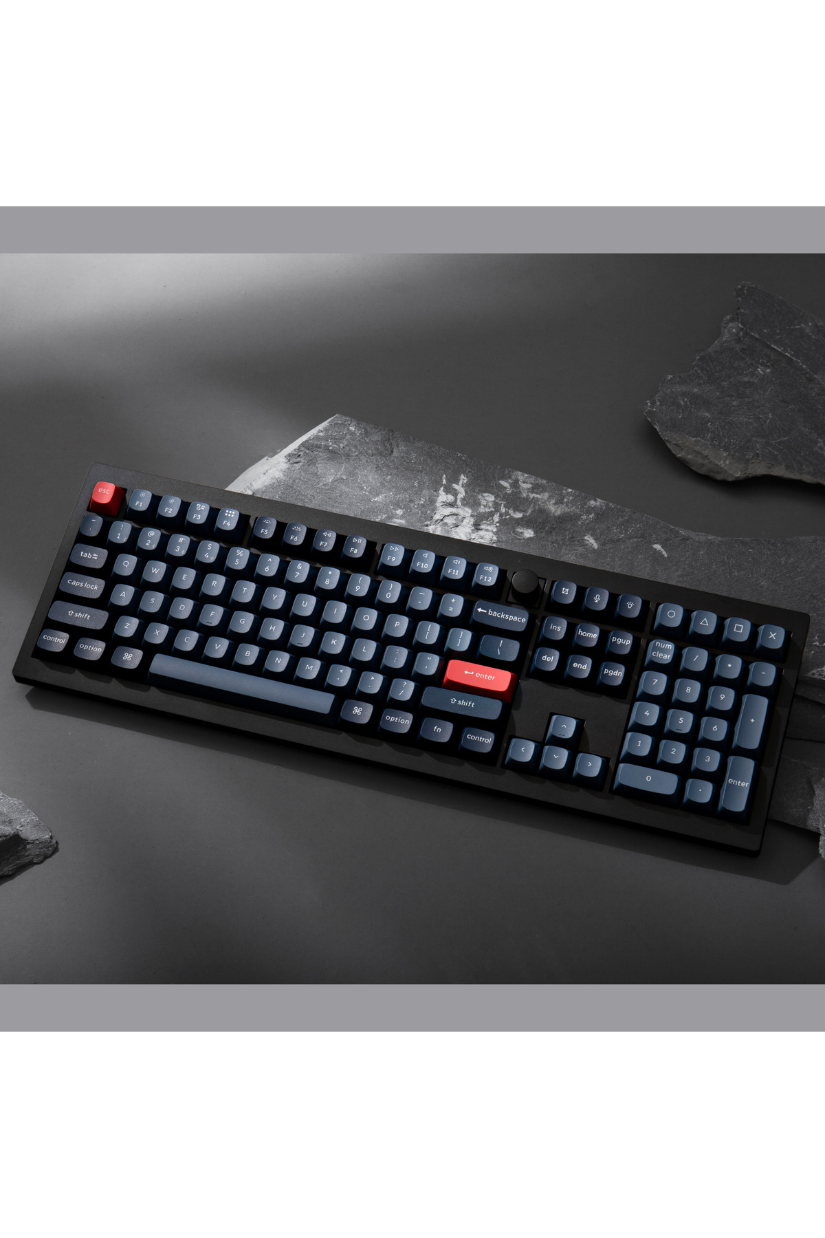 Ciemna klawiatura z czerwonymi klawiszami akcentującymi (Esc, Enter) na szarym tle.