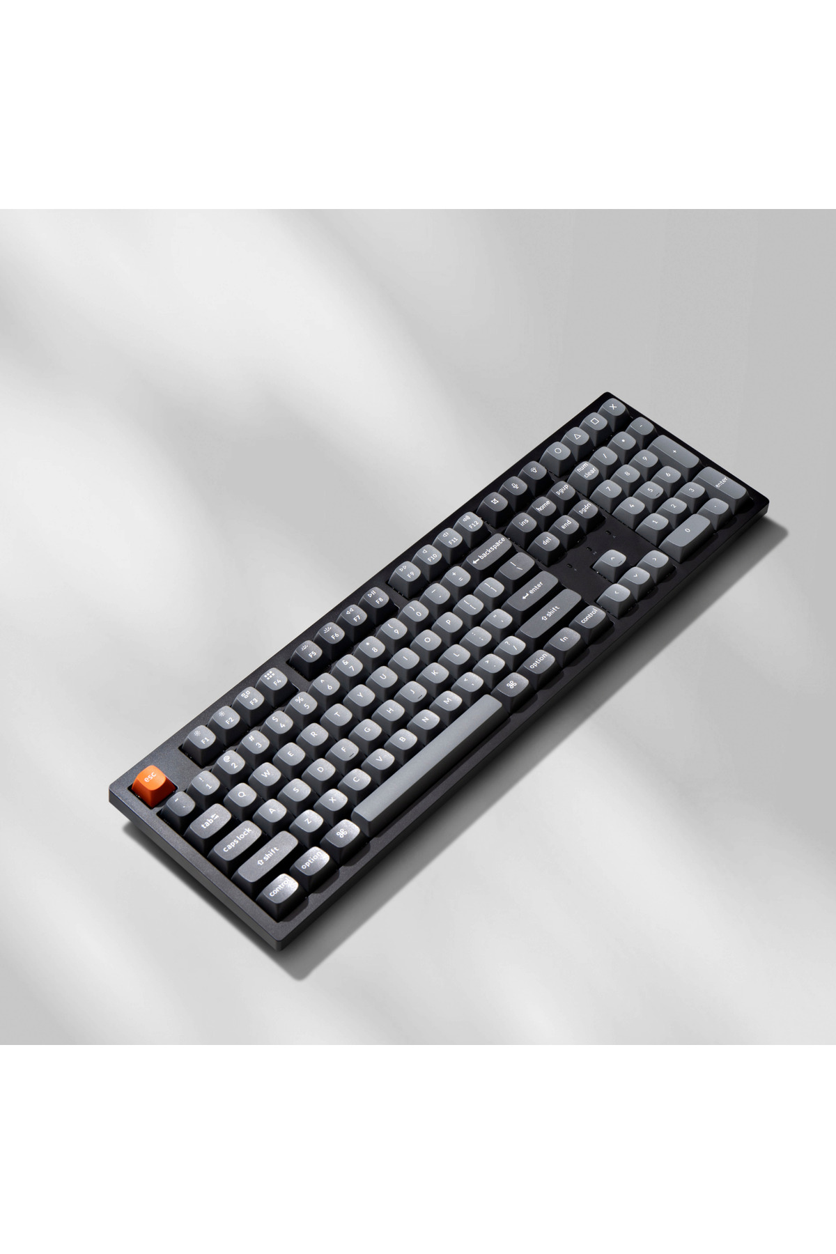 Ciemna klawiatura z szarymi i pomarańczowymi klawiszami na jasnym tle.
