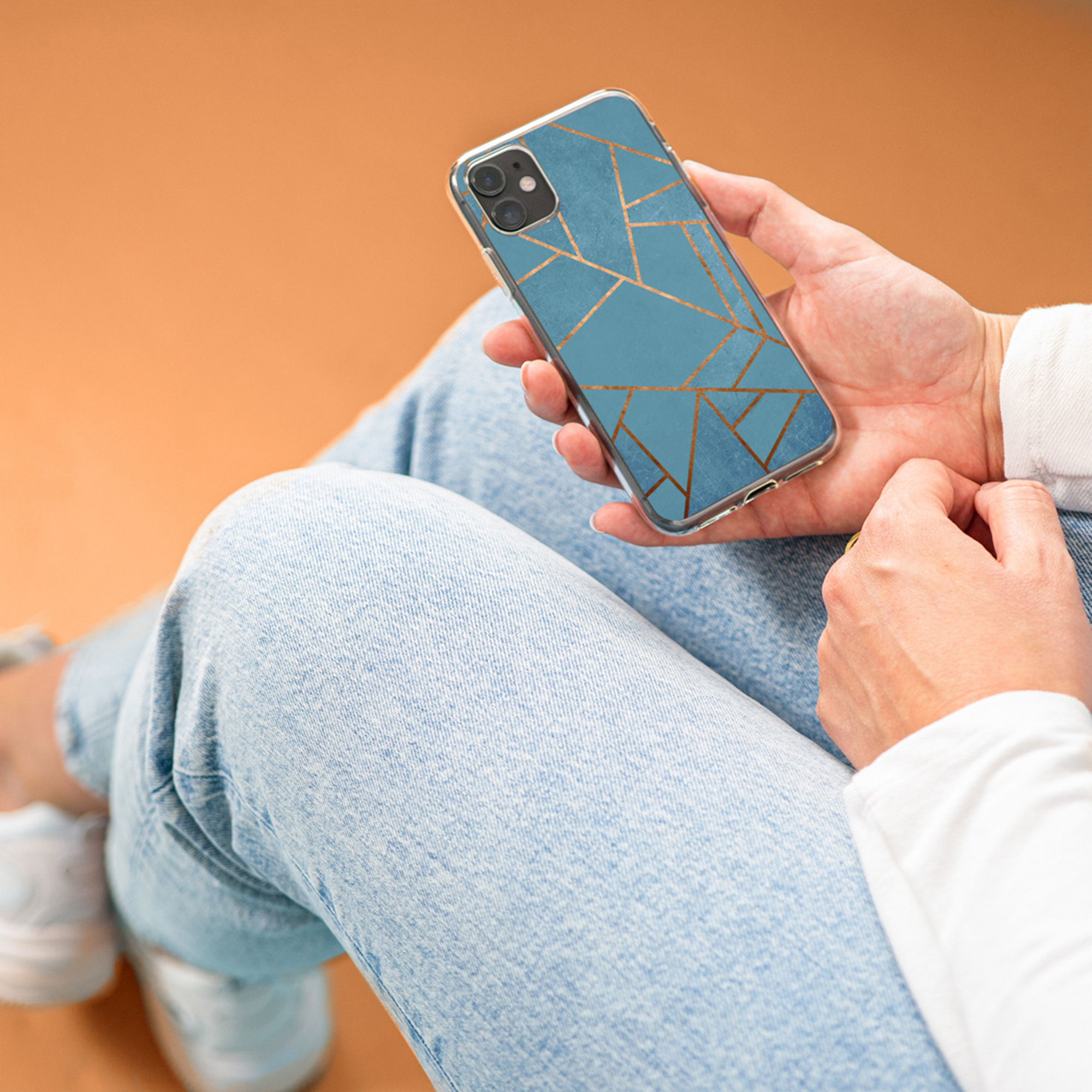 Una persona tiene uno smartphone con motivo a marmo blu e linee dorate.