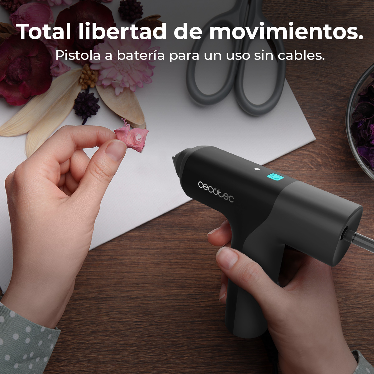 Mani tengono una figura rosa e una pistola per colla nera su tavolo di legno.