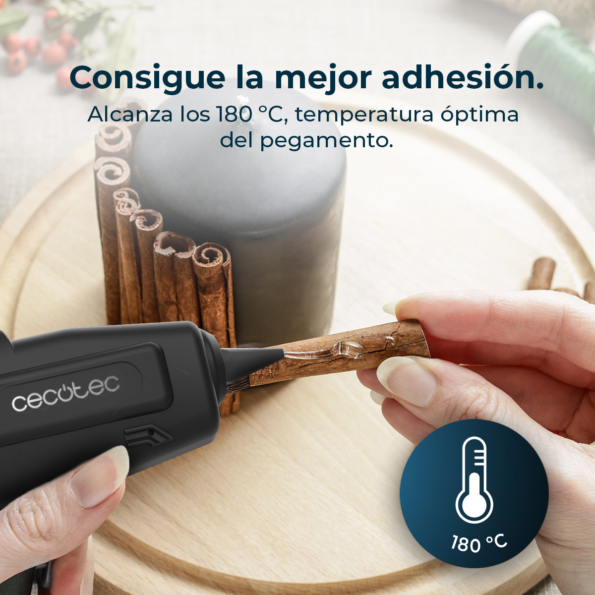 Una mano usa una pistola per colla a caldo per attaccare bastoncini di cannella a una candela. 180°C.