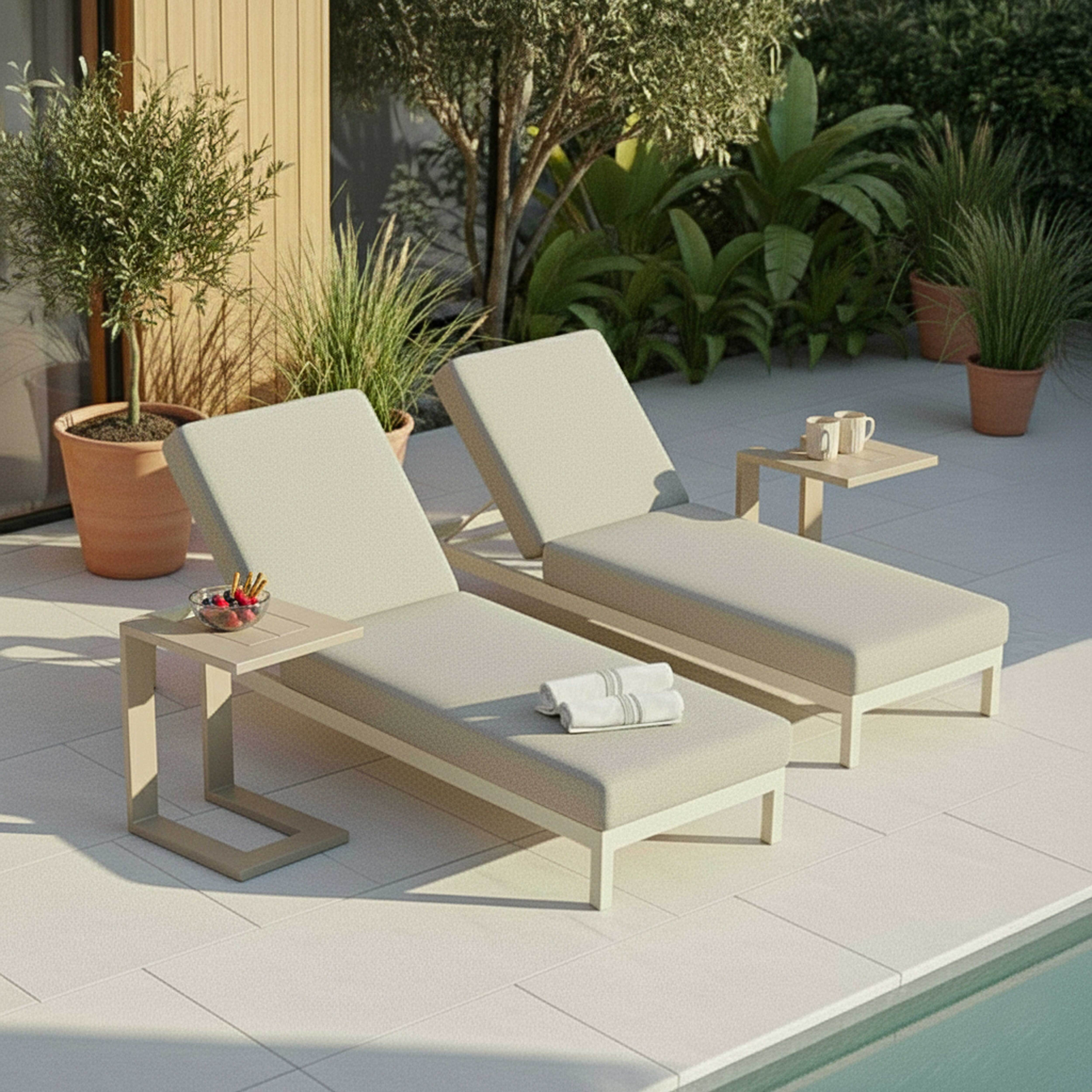 Zwei Liegestühle am Pool mit Beistelltischen, Tassen und Obst.