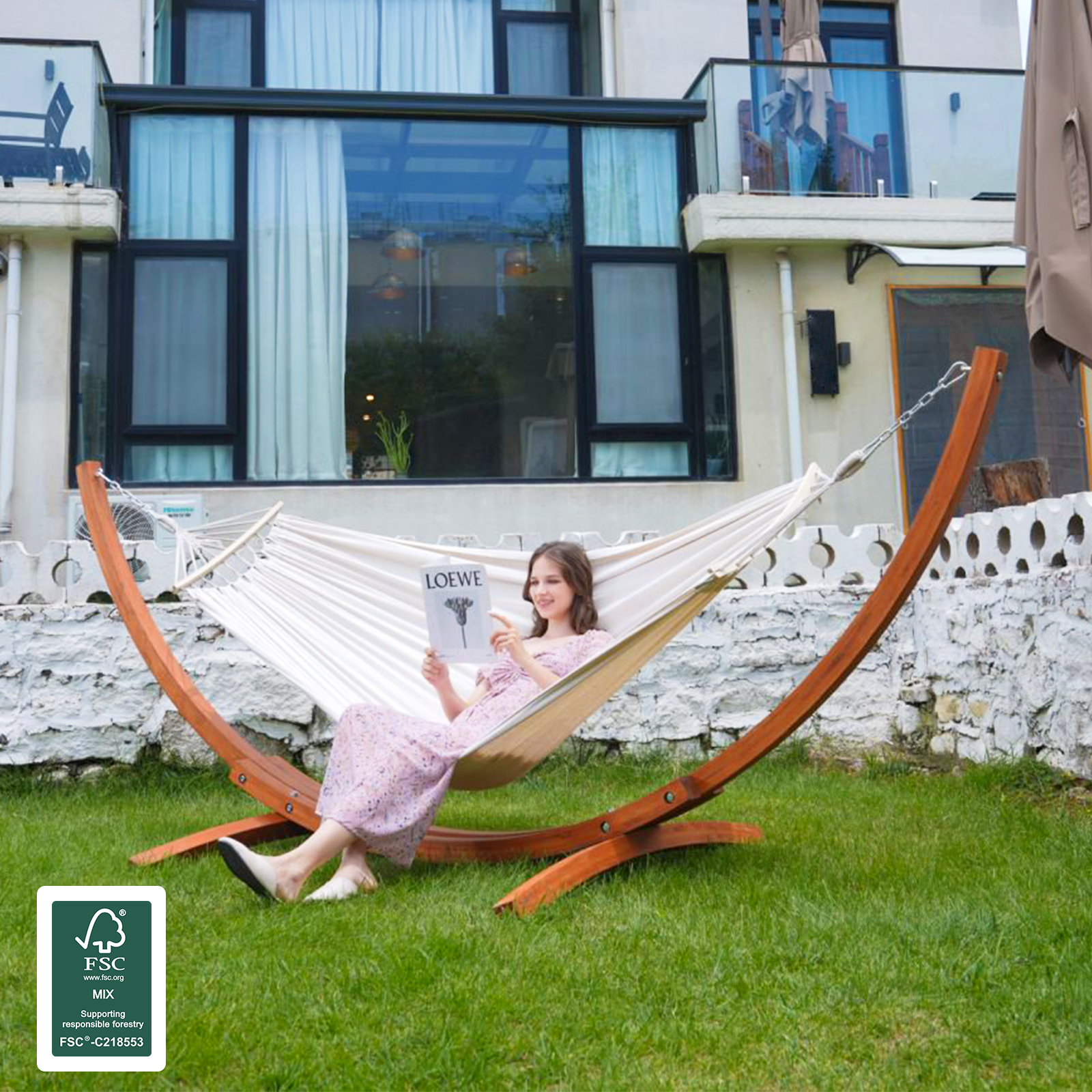 Kobieta czyta w hamaku w ogrodzie z drewnianym stojakiem.