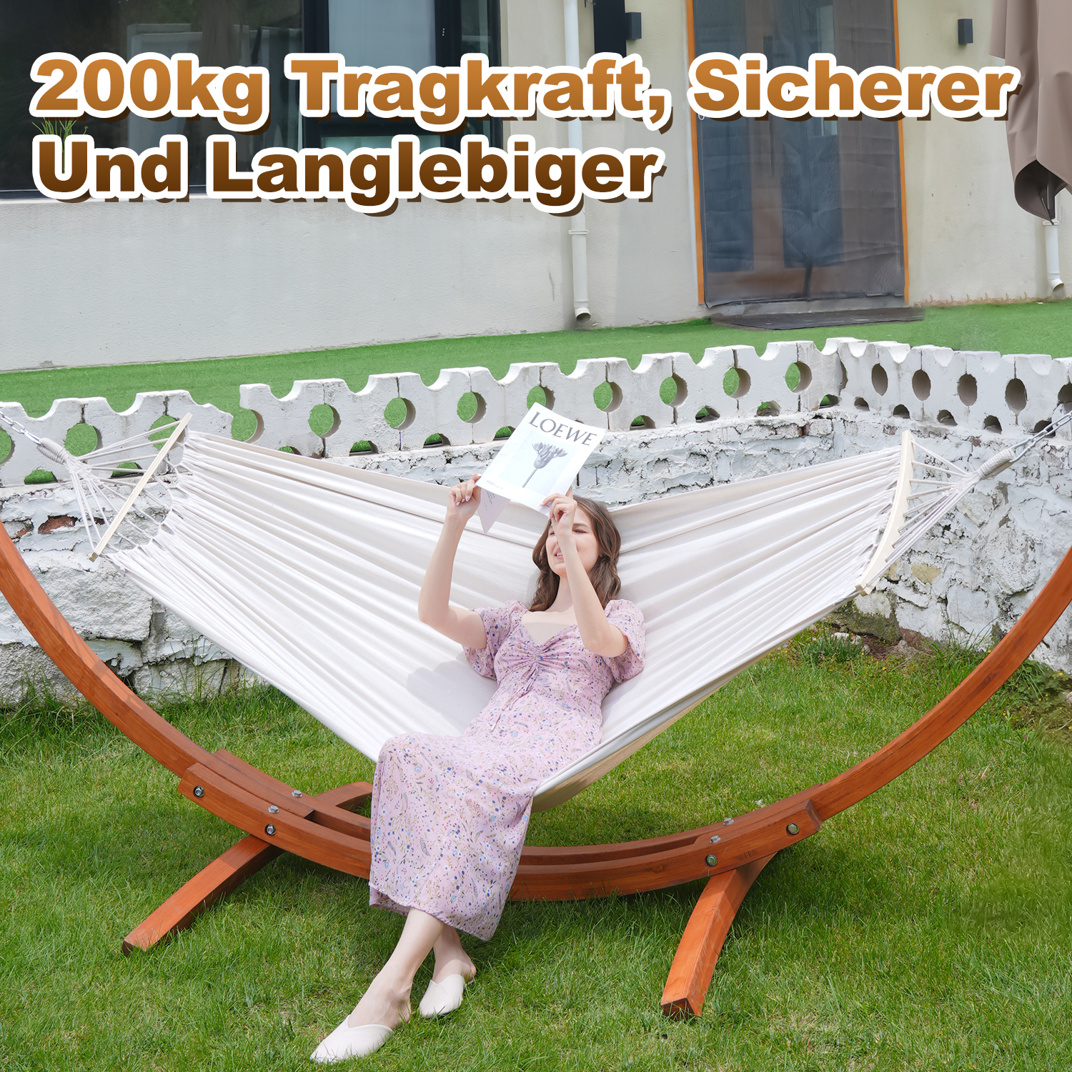 Eine Frau liegt in einer Hängematte und liest ein Buch. Sie trägt ein Kleid mit Blumenmuster.