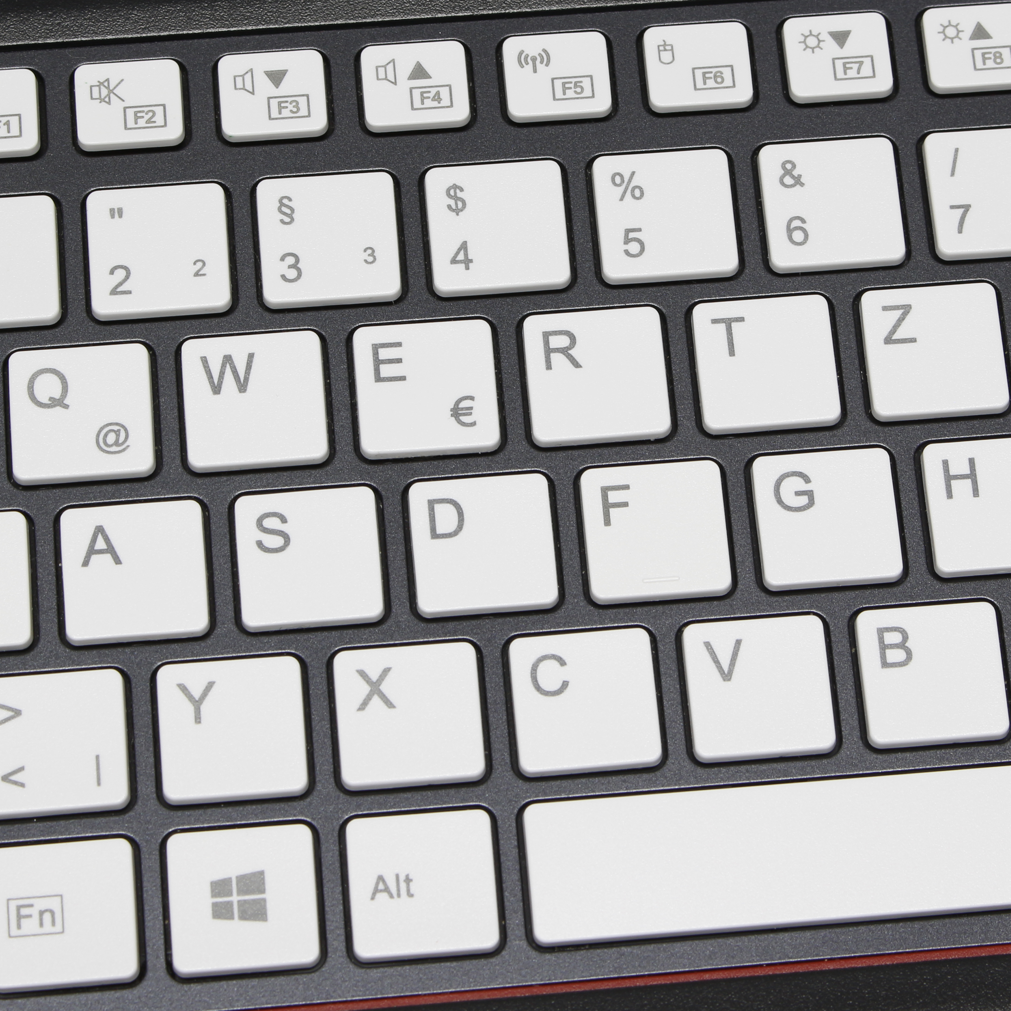 Primer plano de un teclado blanco con etiquetas de teclas negras. Teclas F arriba.