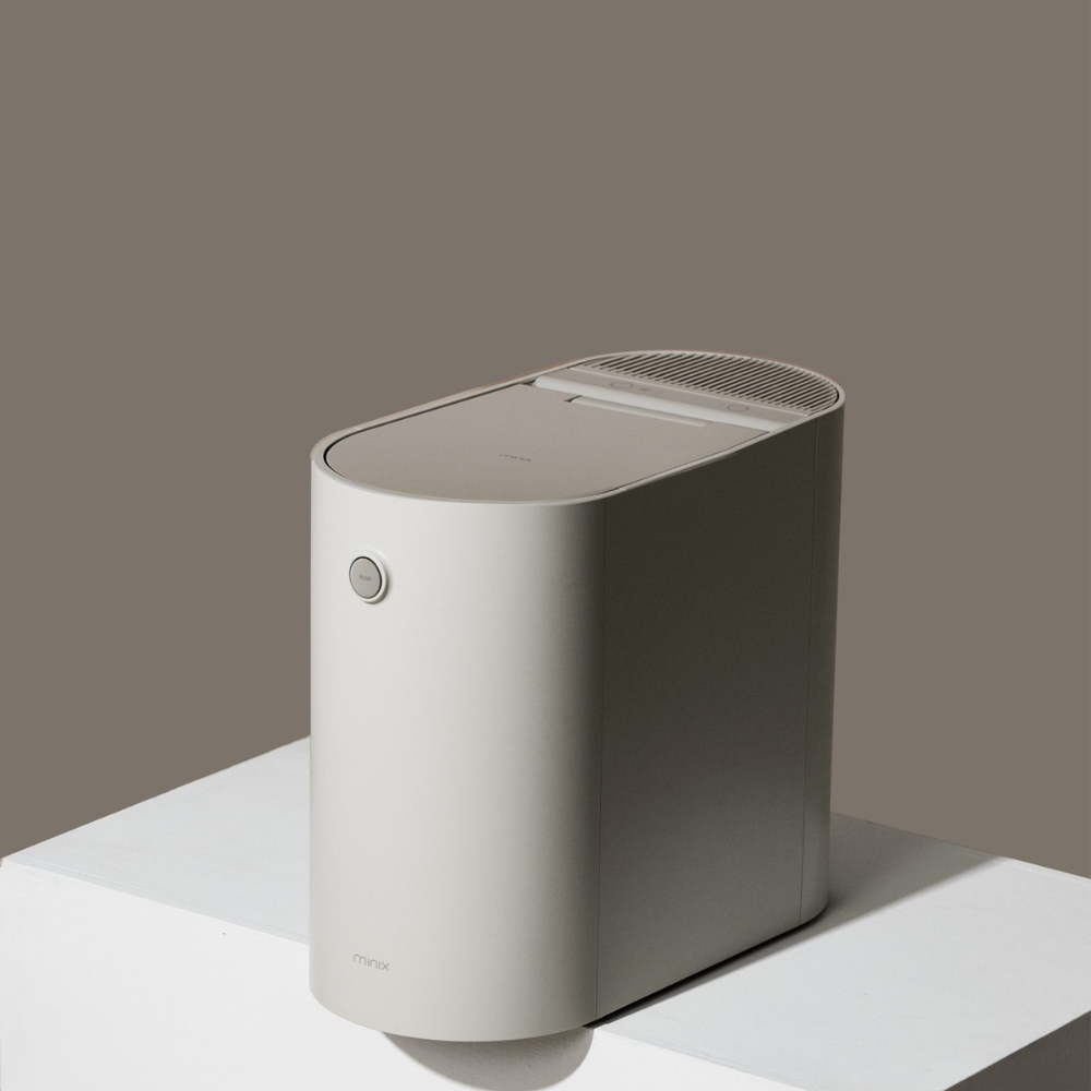 Un purificatore d'aria grigio con angoli arrotondati è su un piedistallo bianco.
