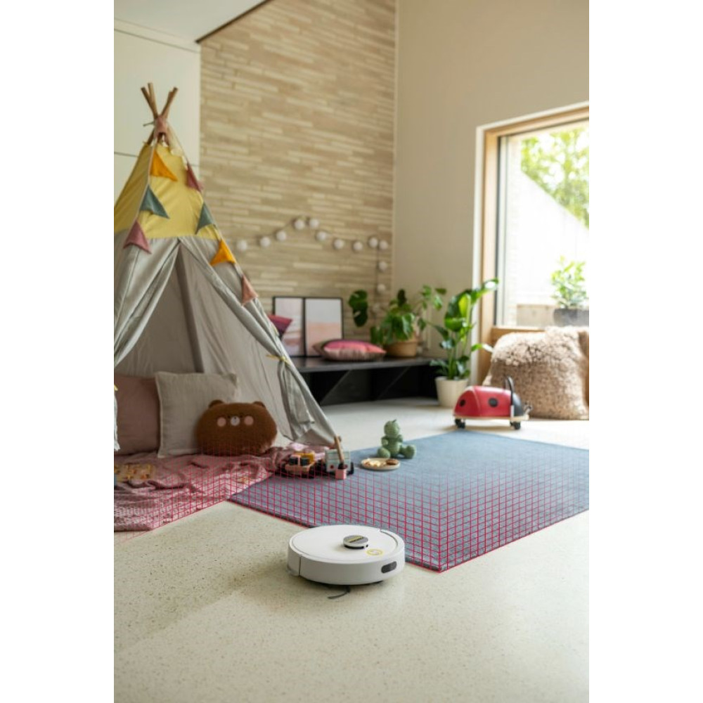 Biały robot sprzątający czyści dywan w pokoju zabaw z tipi i zabawkami.