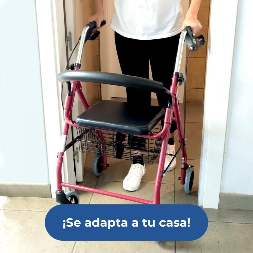 Un andador rojo con asiento y cesta está en un pasillo.