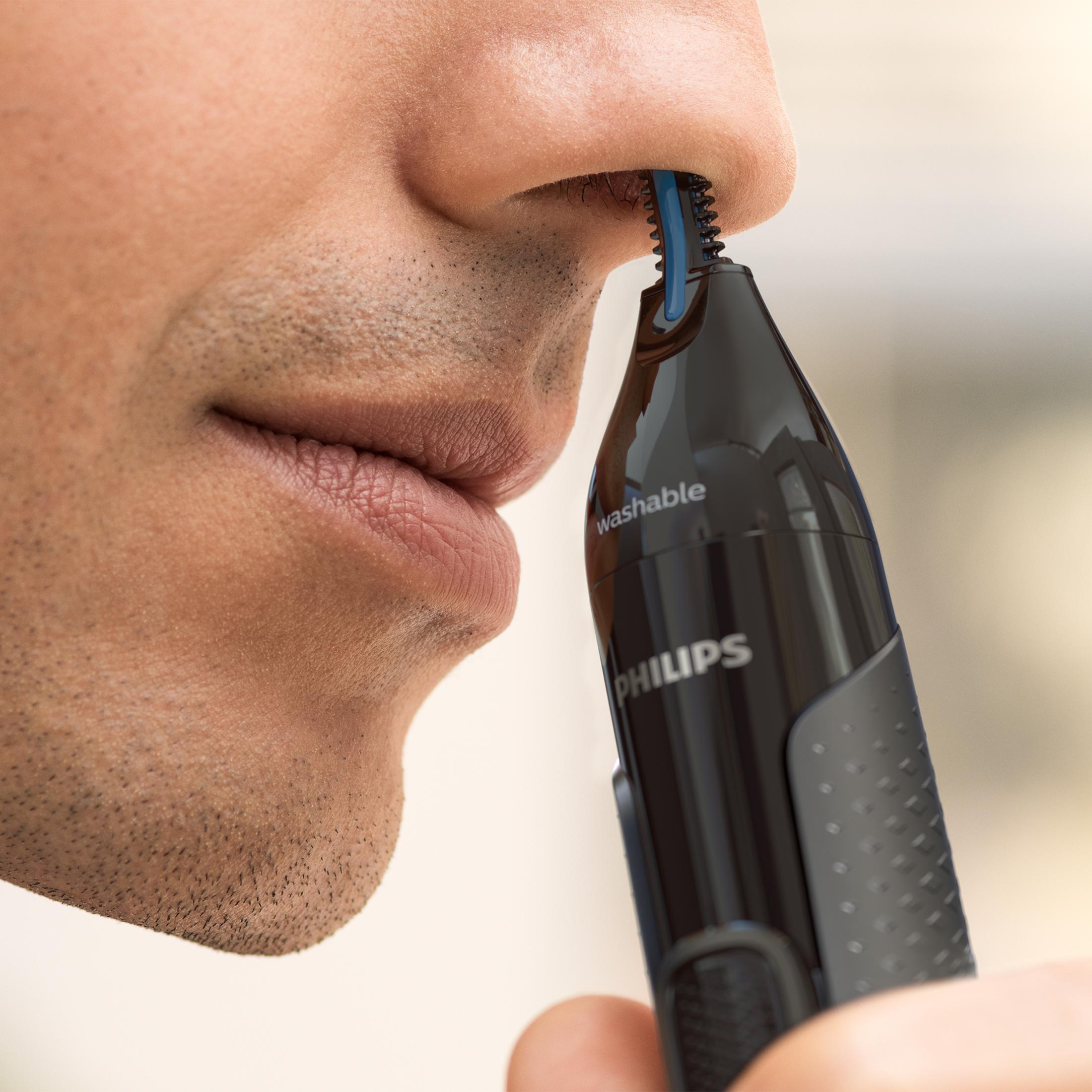 Primo piano di un uomo che si taglia i peli del naso con un rifinitore Philips.