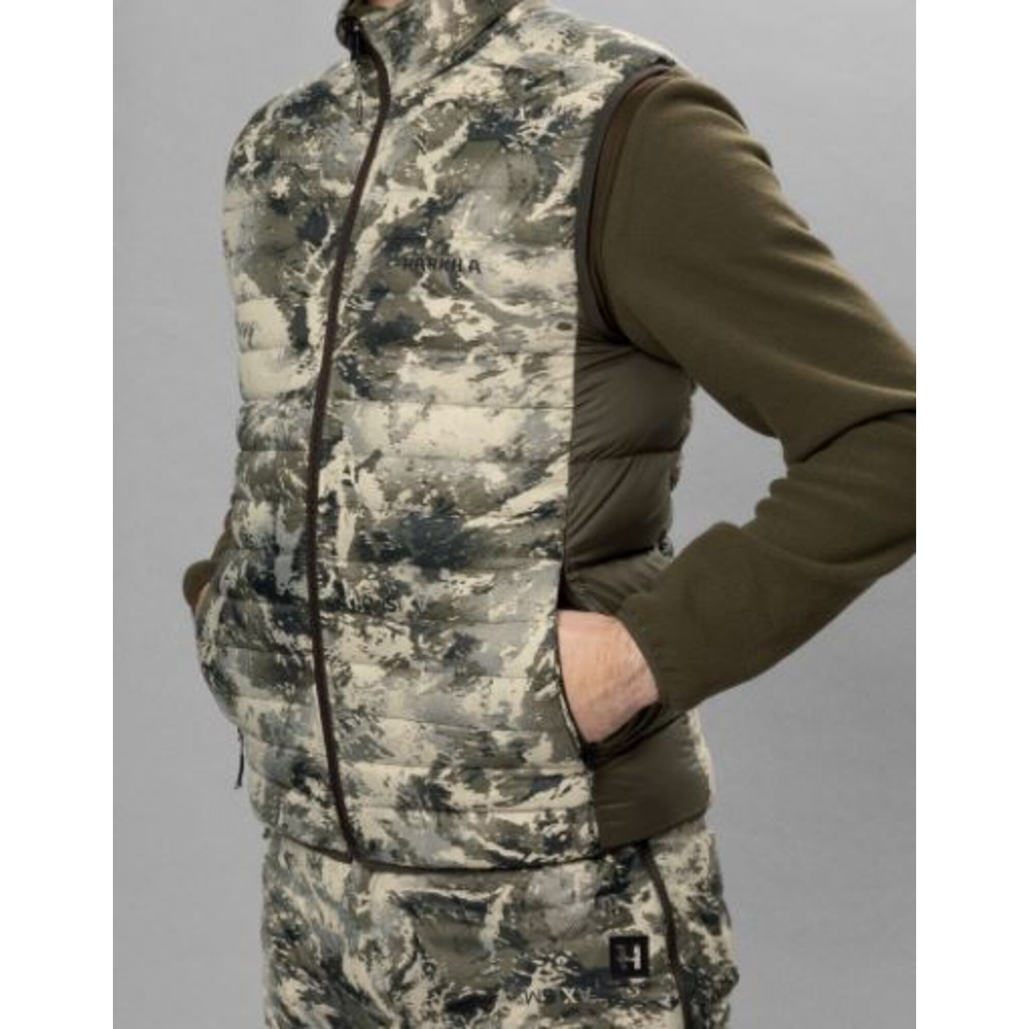Person in Tarnkleidung: gepolsterte Weste über Fleecejacke.